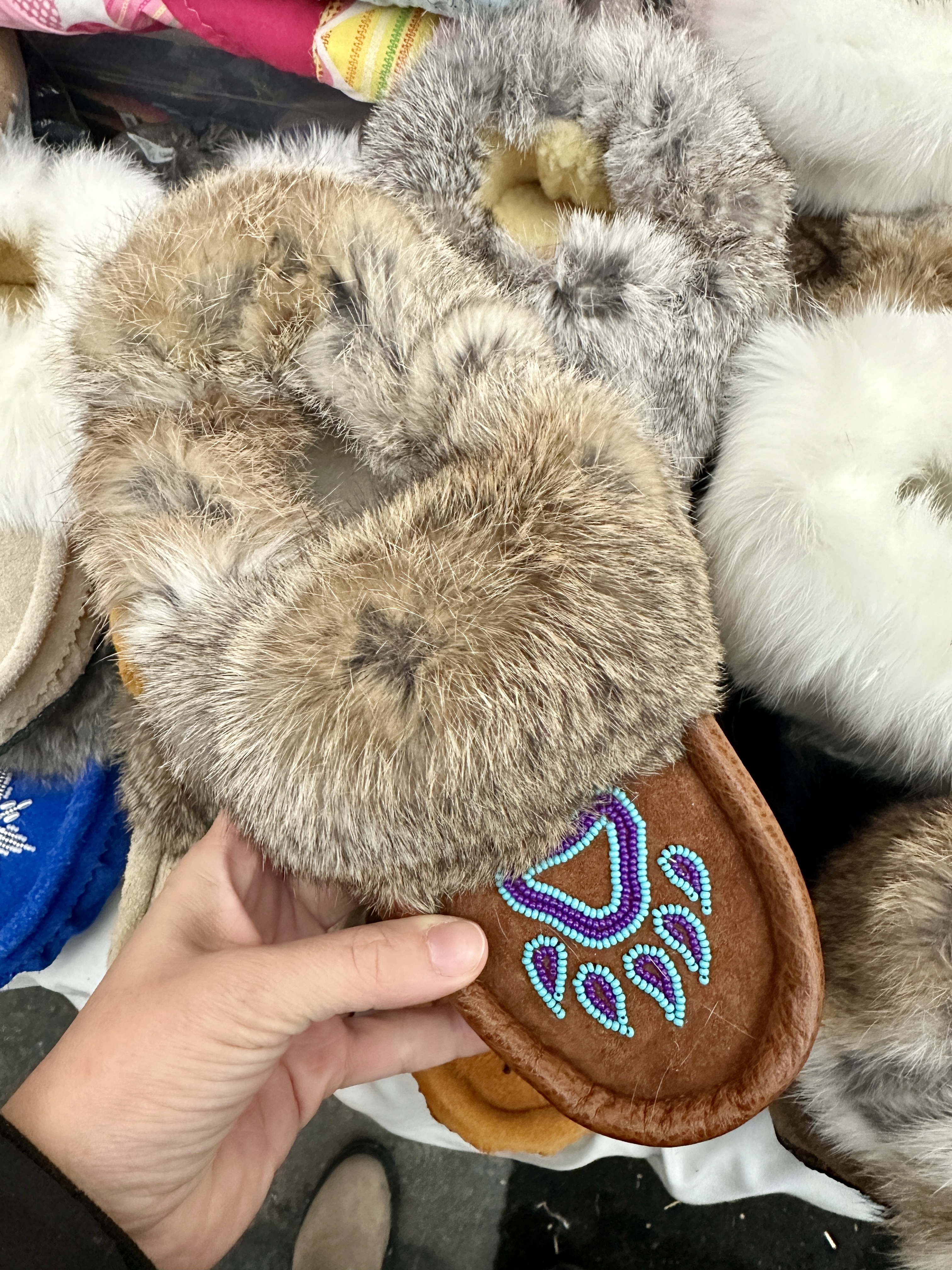 A pair of handmade moccasins with a bear paw design on them
