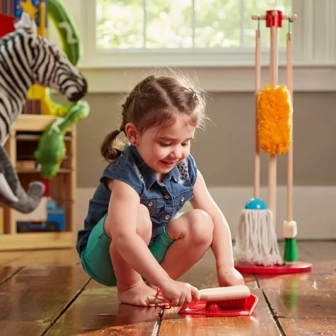 A toddler plays with a cleaning set