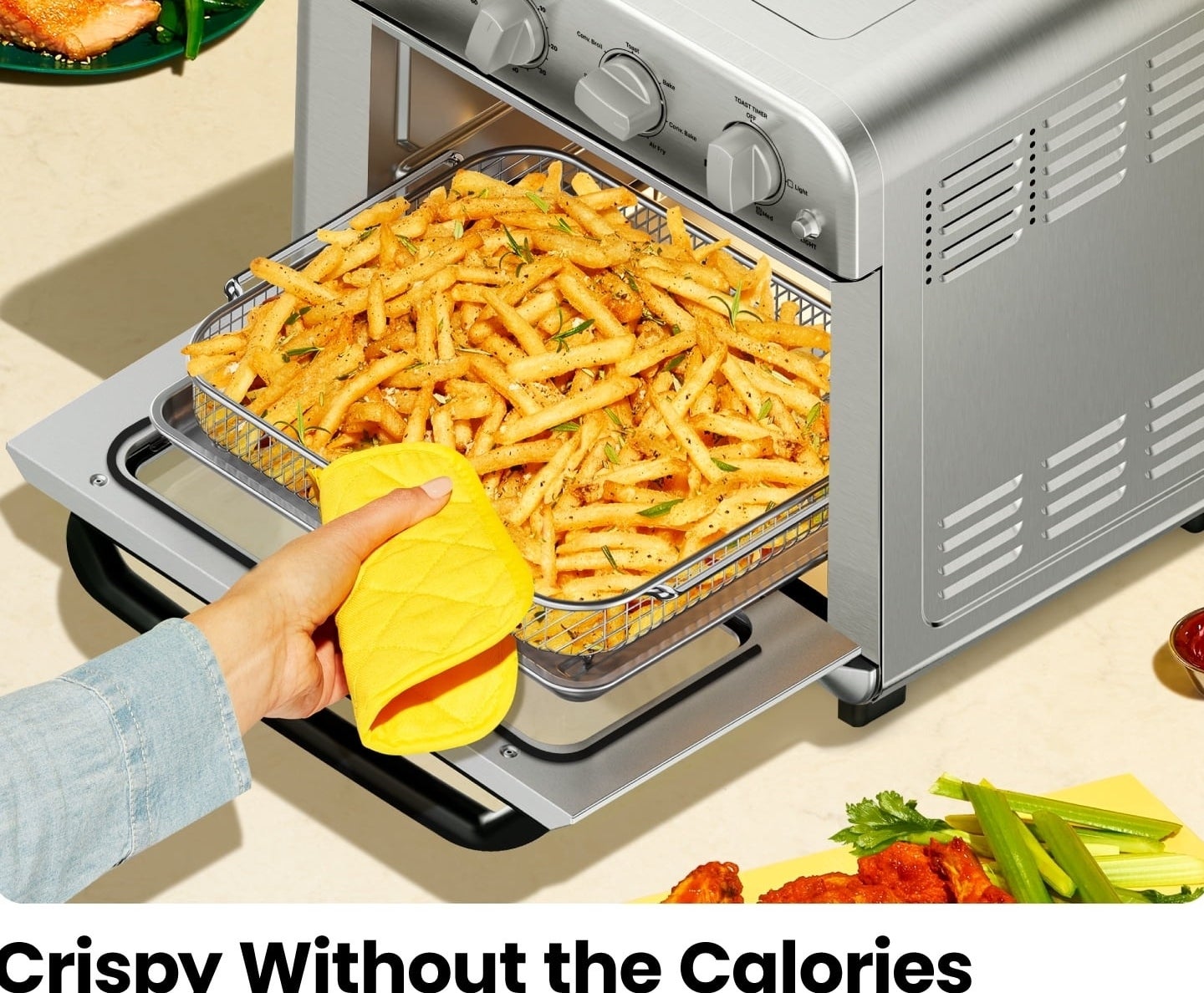 A hand pulls fries out of an air fryer