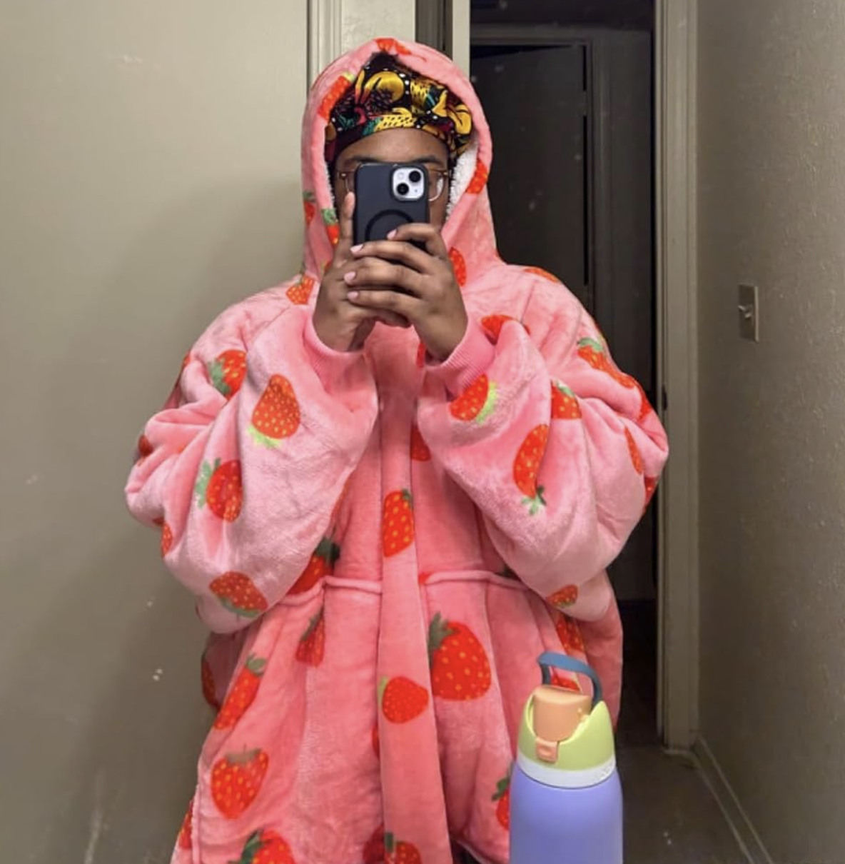 Reviewer taking mirror selfie in bright pink hooded oversized sweater with red strawberries printed on it