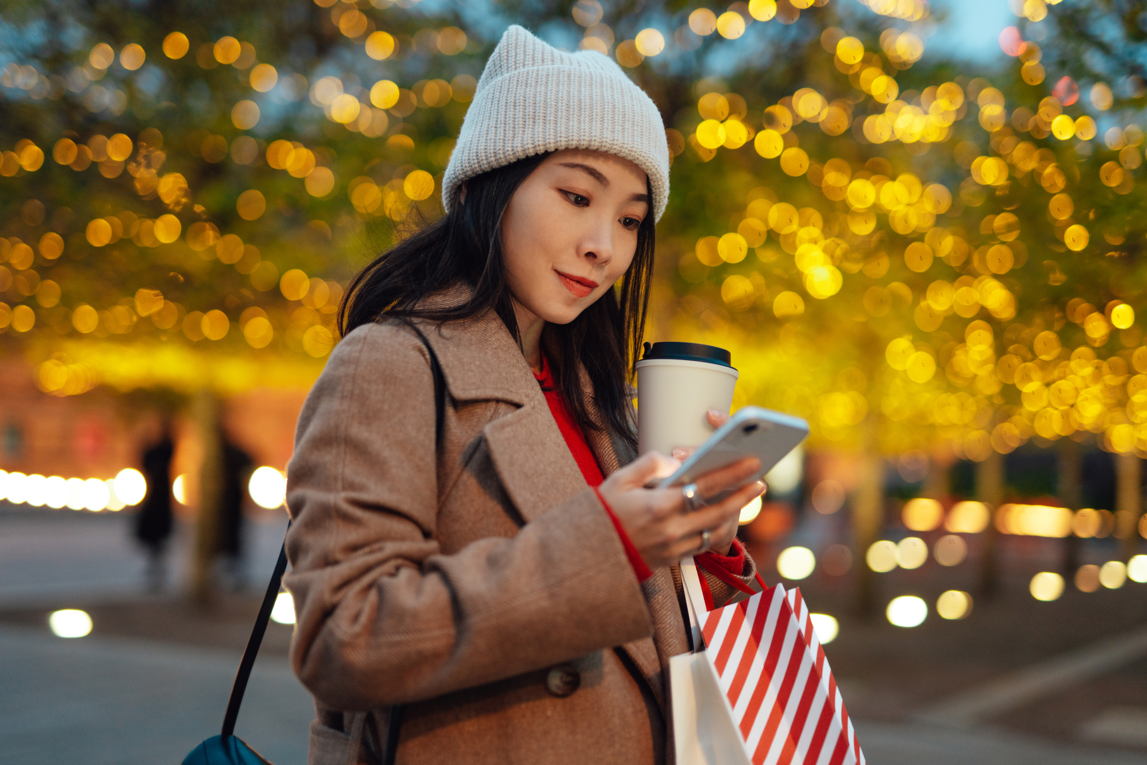 young woman checking her smartphone while out christmas shopping