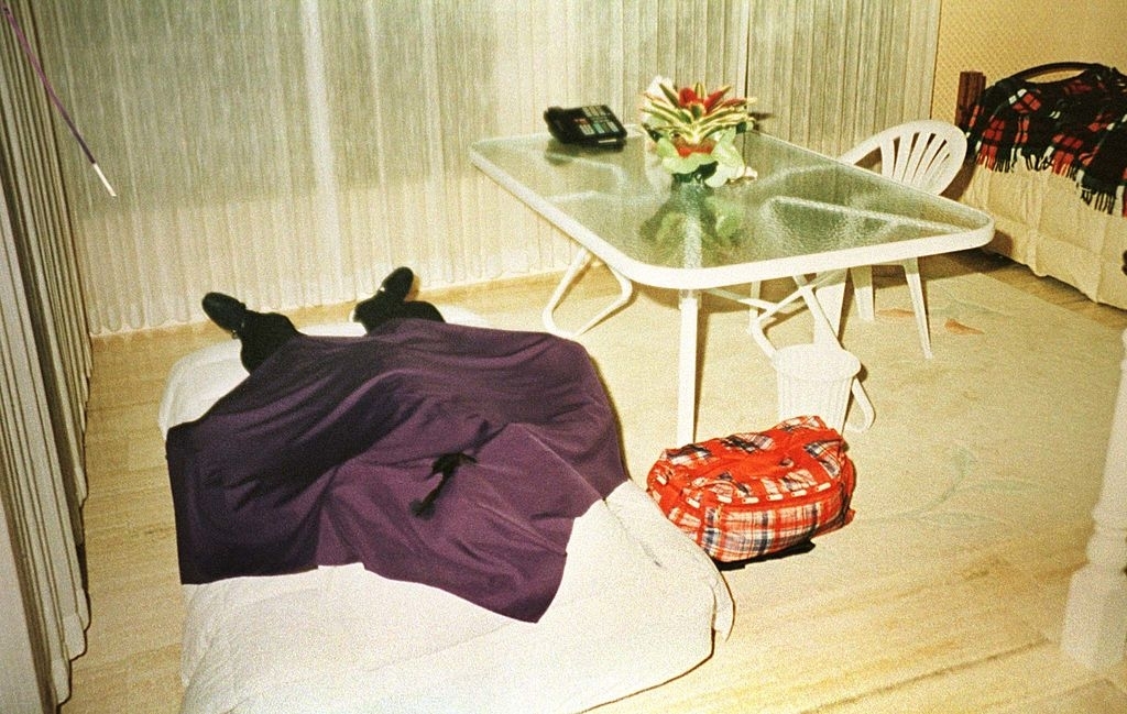 A member of the group, dead, covered with a purple sheet and wearing nike sneakers