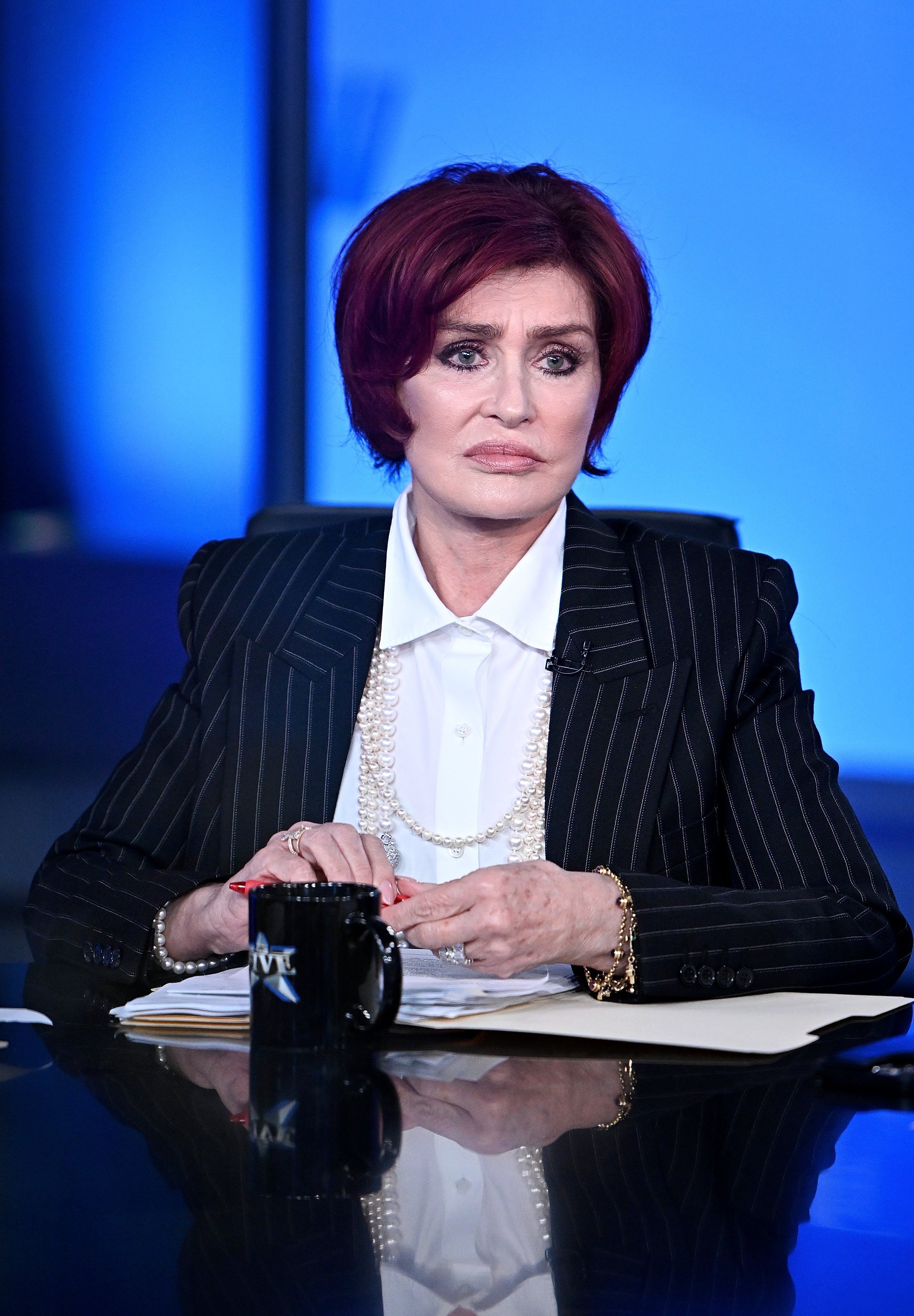Sharon Osbourne sitting at a table on set