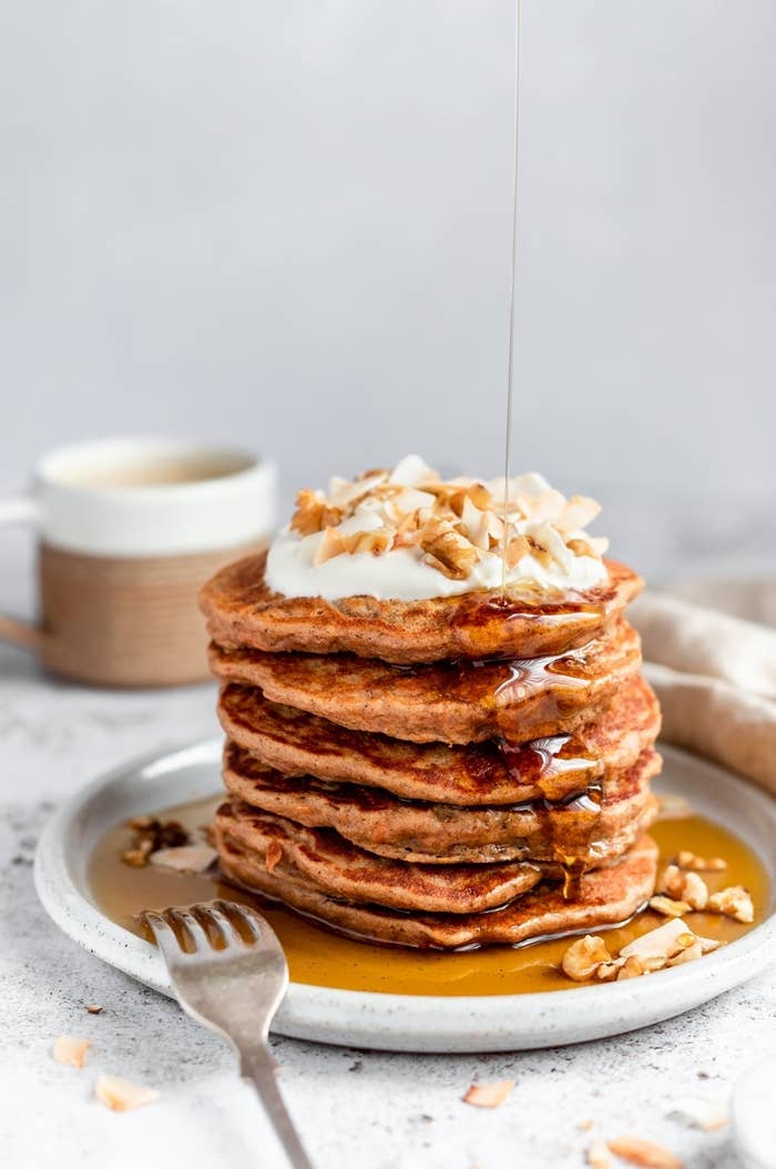 A stack of pancakes being drizzled with maple syrup