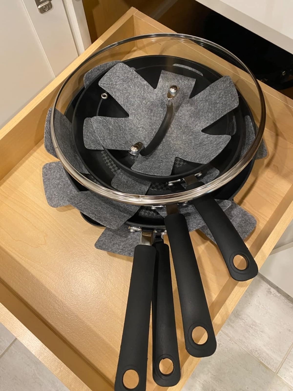 gray felt pot and pan protectors in between stacked black pans