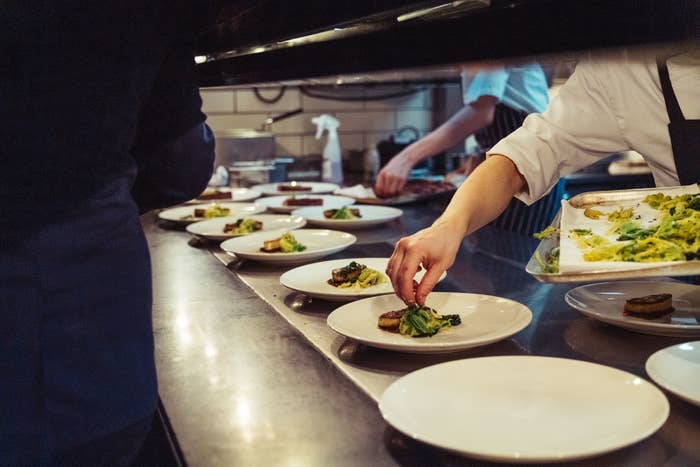 A closeup shot of the chefs preparing a fine dinner at the kitchen in a restaurant in London, England