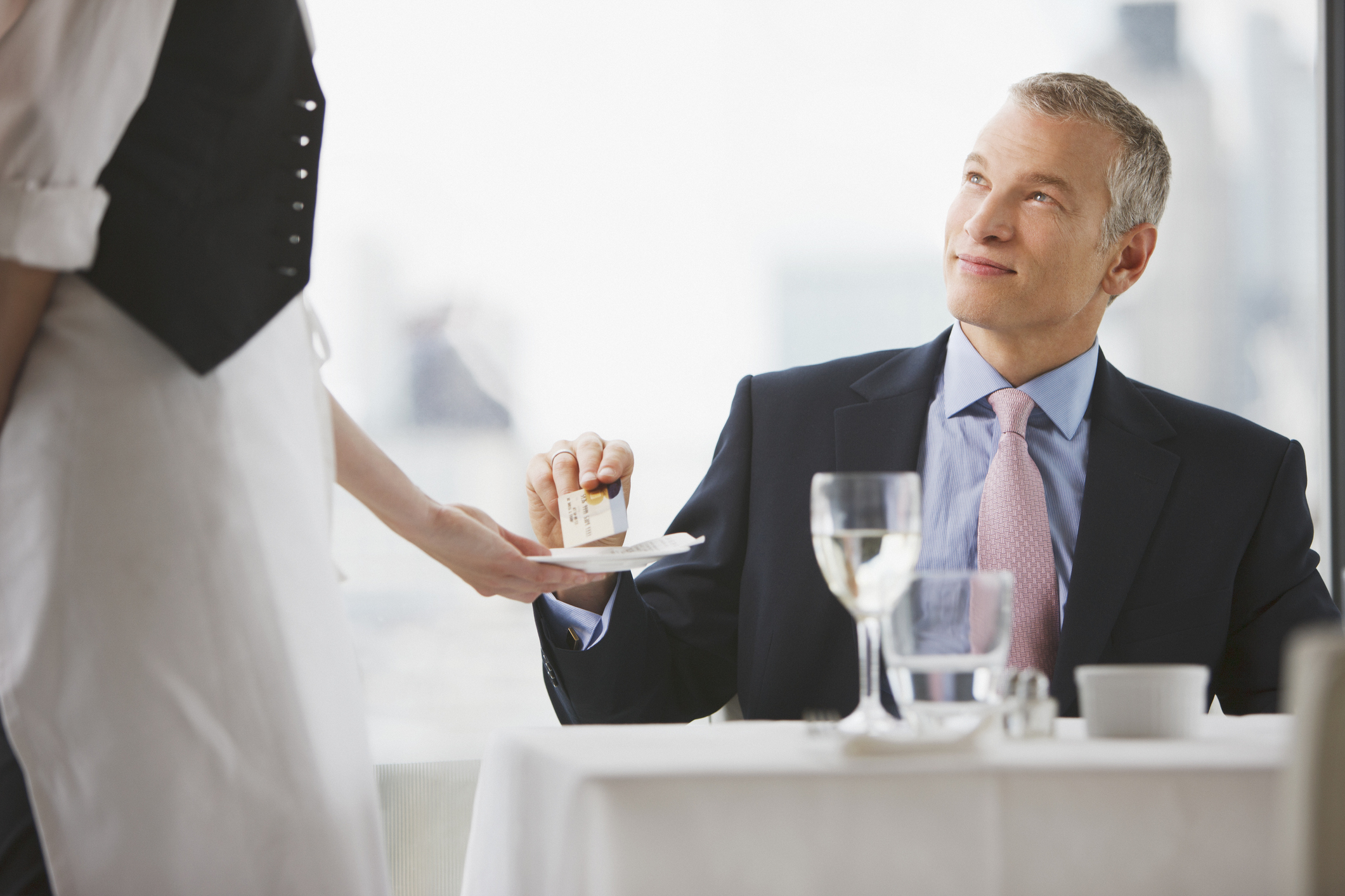 Businessman handing waitress credit card in restaurant
