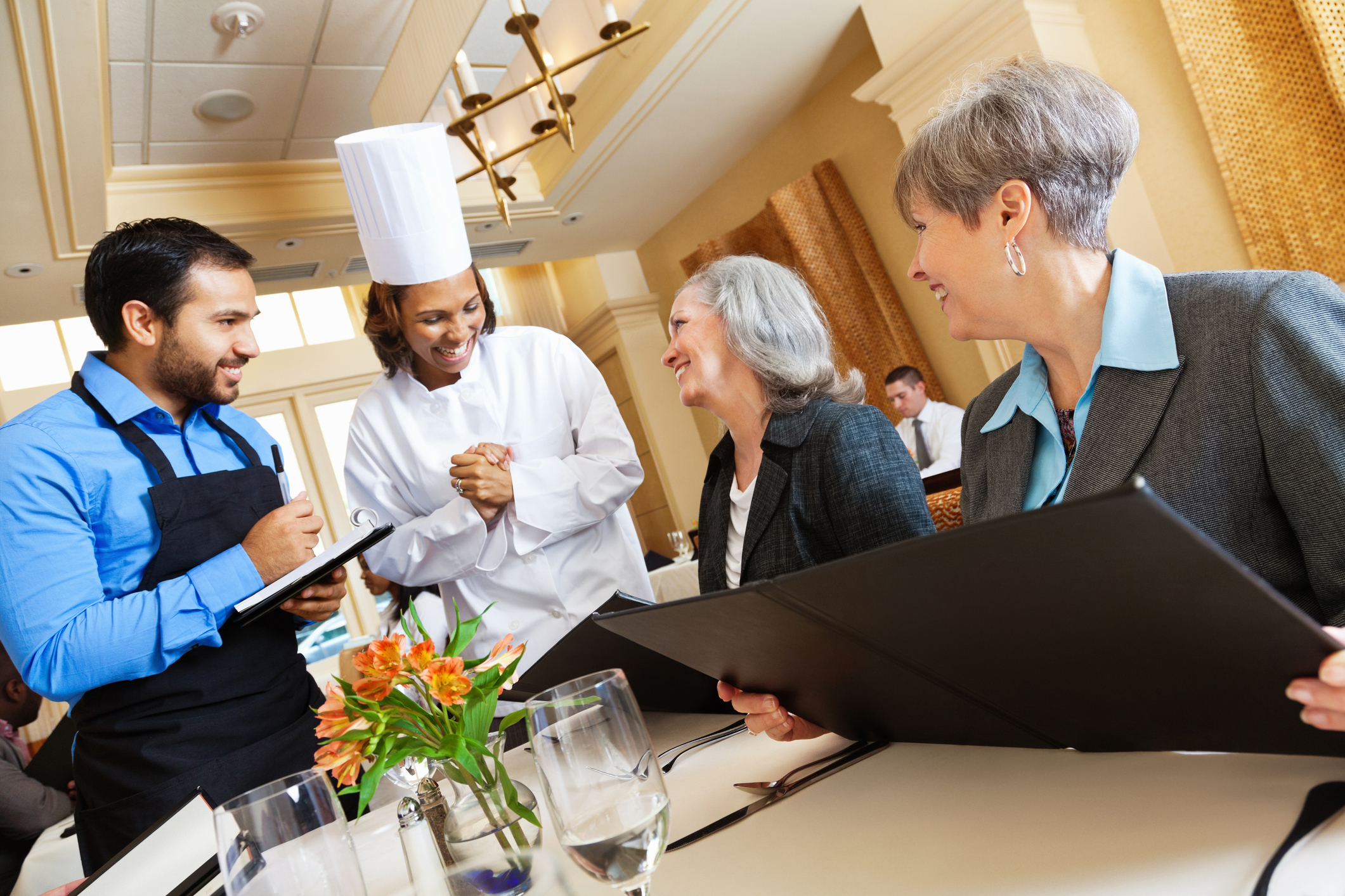 Restaurant chef and waiter helping customers with menu food questions