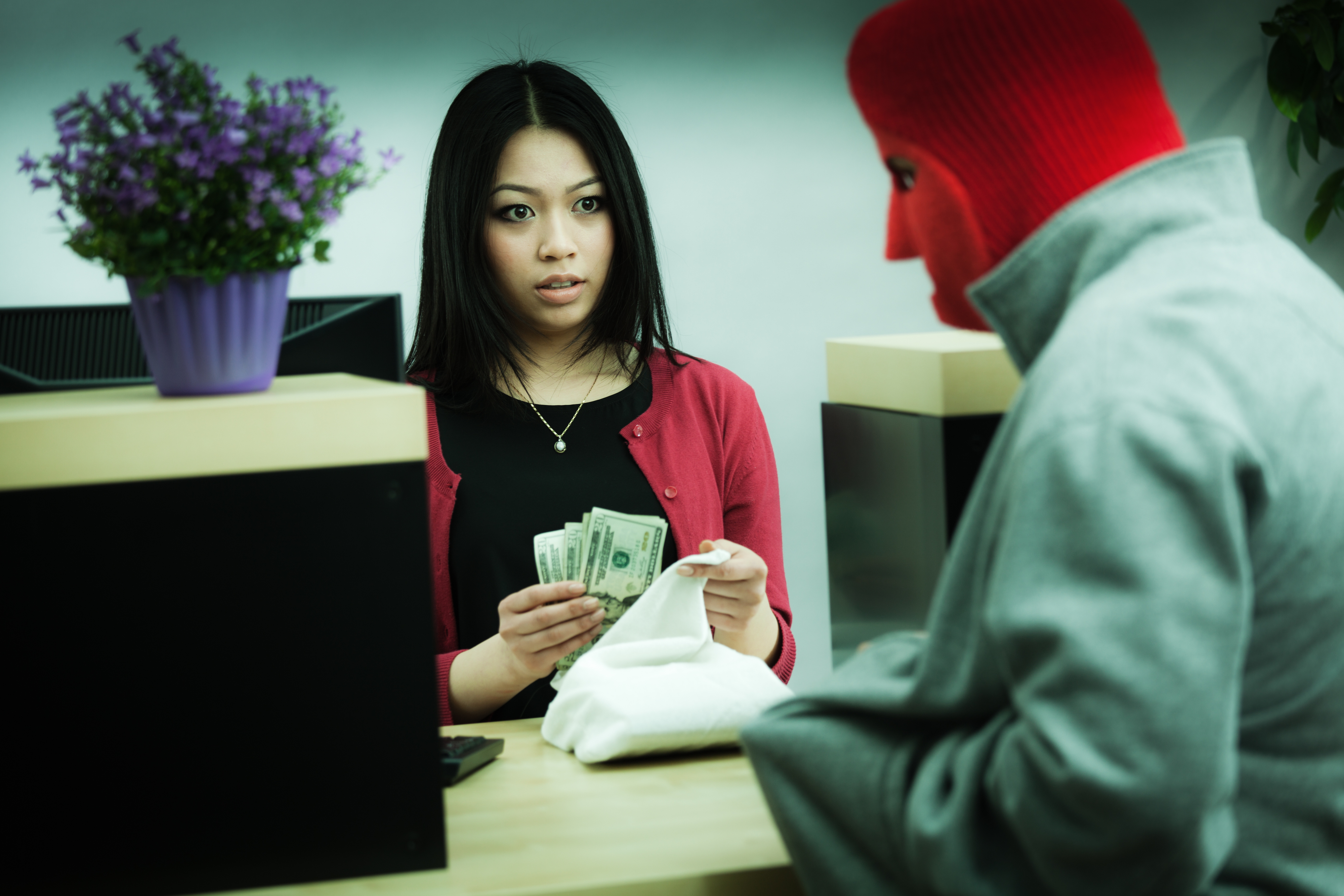 bank teller putting money in a bag for a person with a face mask