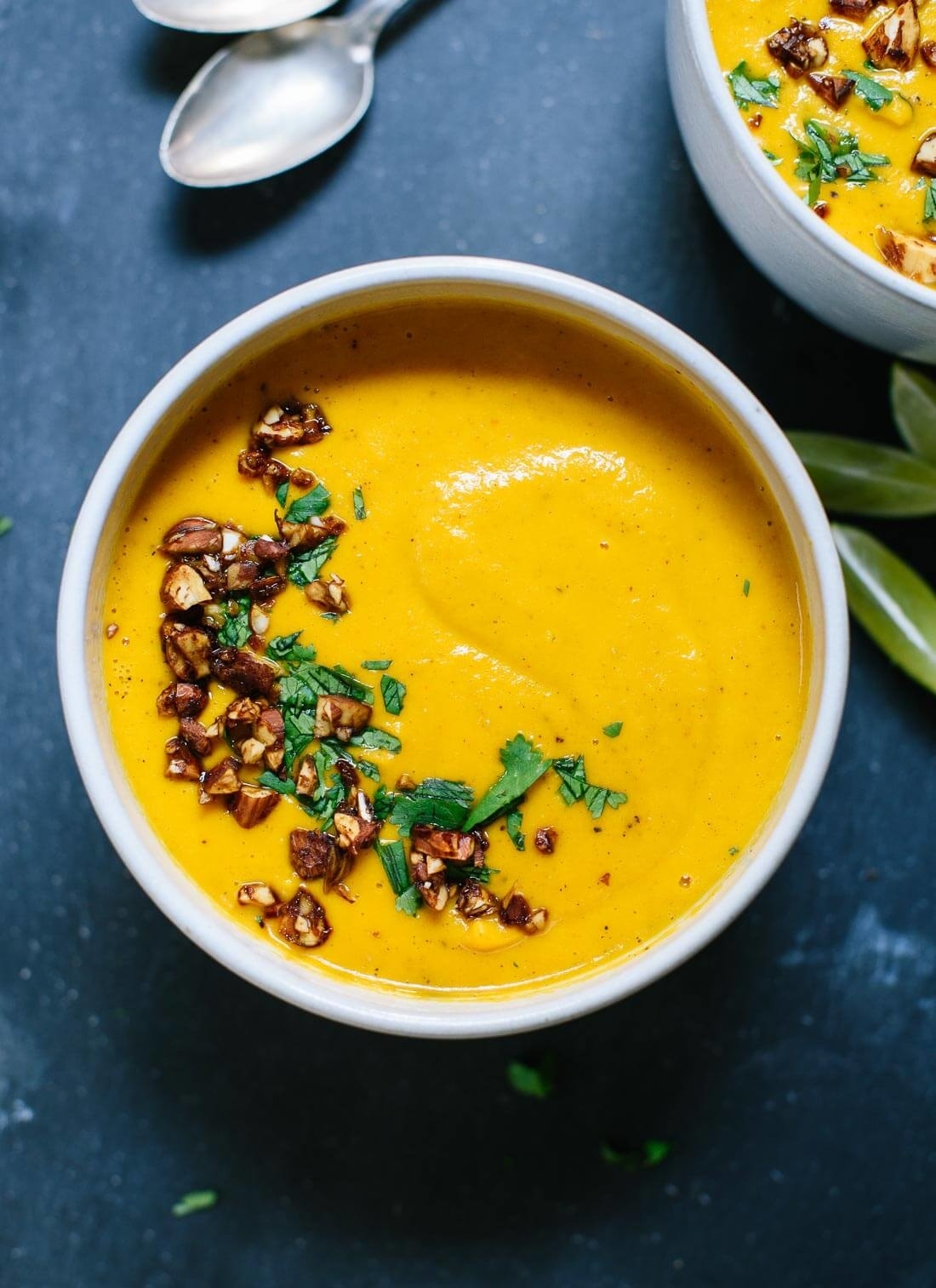 A bowl of Thai carrot sweet potato soup topped with almonds and fresh herbs