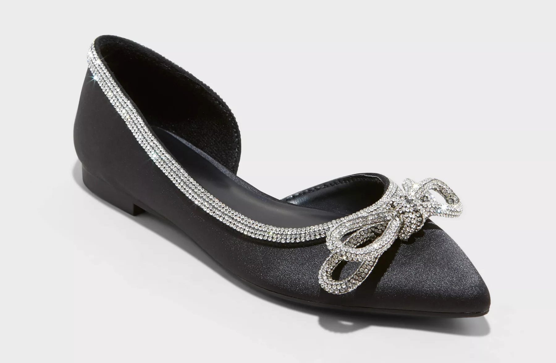 The pointed-toe satin flats, decorated with a knotted rhinestone bow and trim