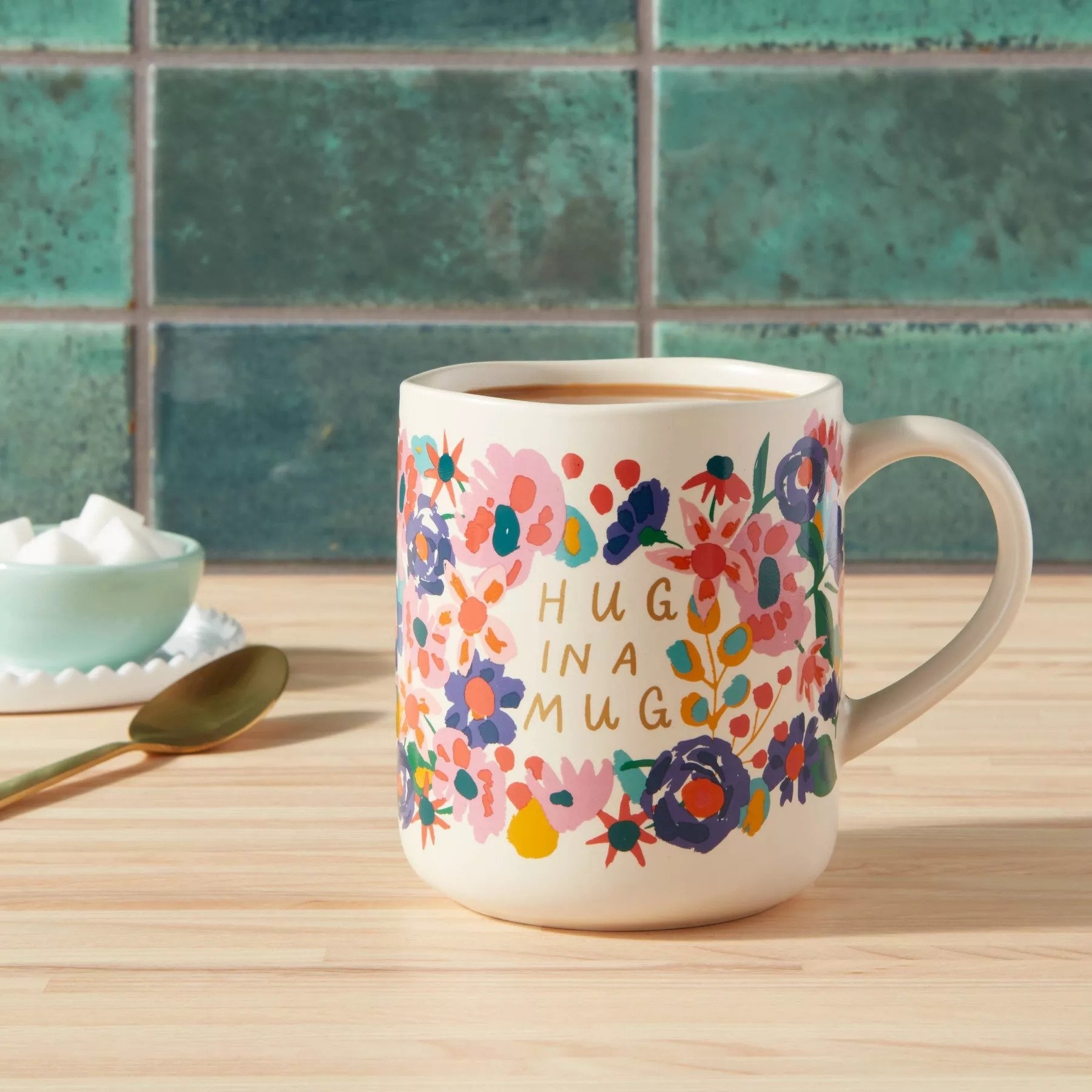 The mug featuring a floral design and the words hugs in a mug in the front
