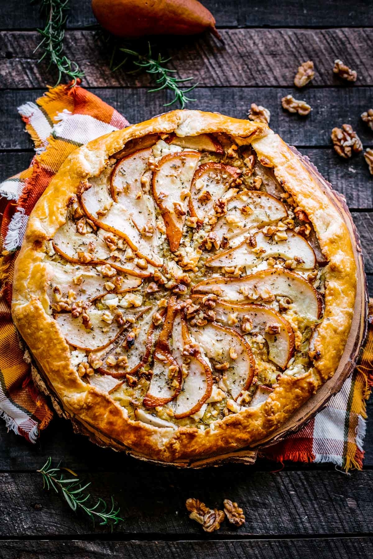 A round galette with sliced pears and chopped walnuts