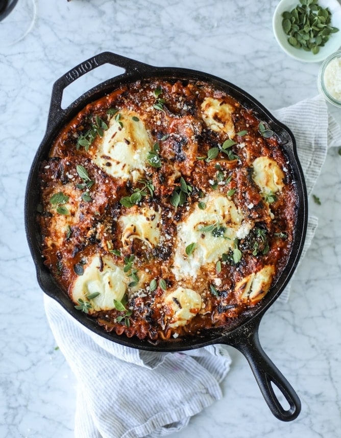 Kale, sausage, and lasagna noodles in a cast-iron skillet with dollops of ricotta