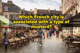 People eat on sidewalk patios and a man rides his bike through Dijon, France.