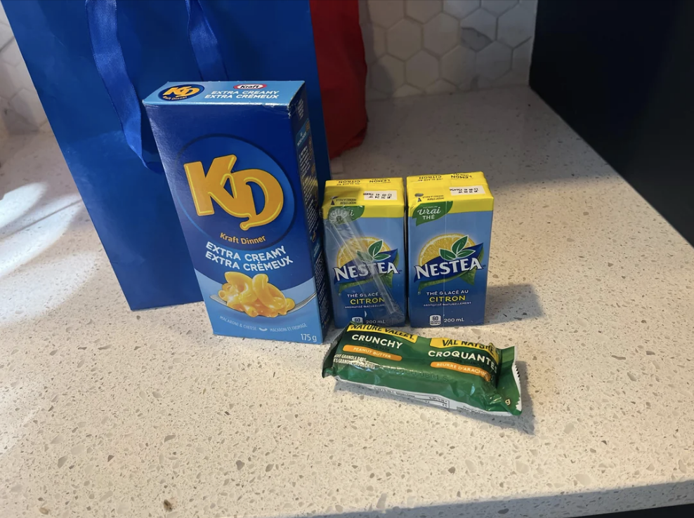 A box of kraft mac n&#x27;cheese, a nature valley bar, and 2 juice boxes on a countertop