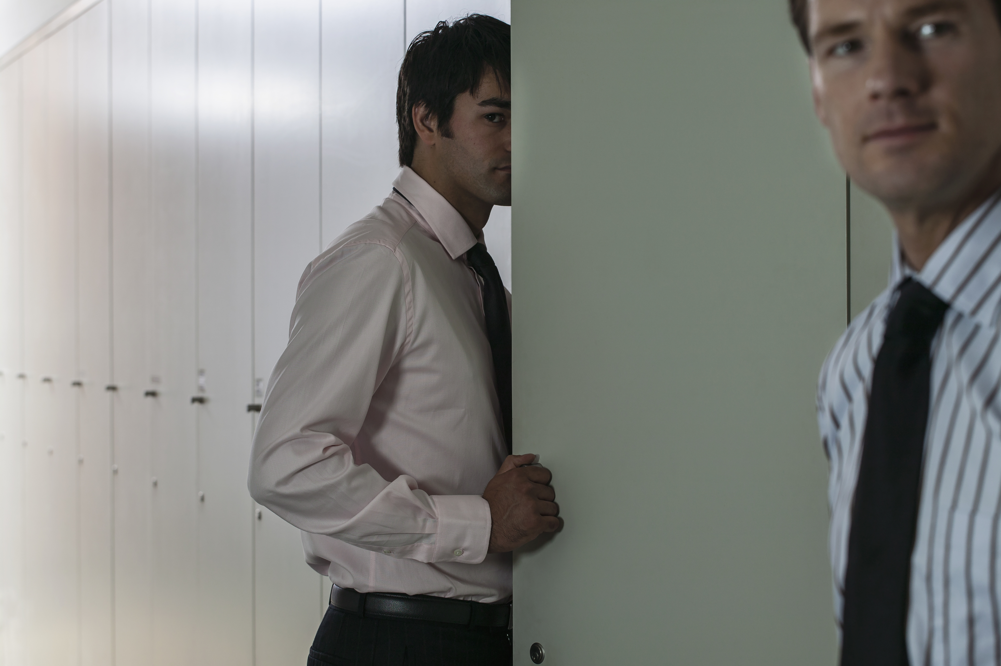 a sneaky businessman gives a sidelong look to another businessman, who has his back turned