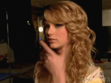 Taylor Swift rubs her chin, pondering.