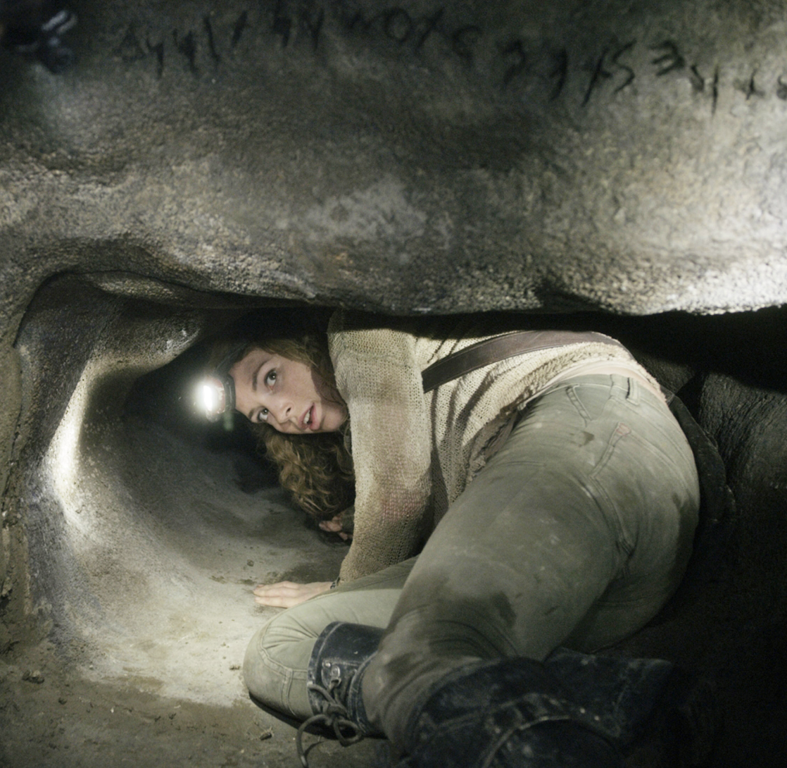 A woman crawling in a small cave
