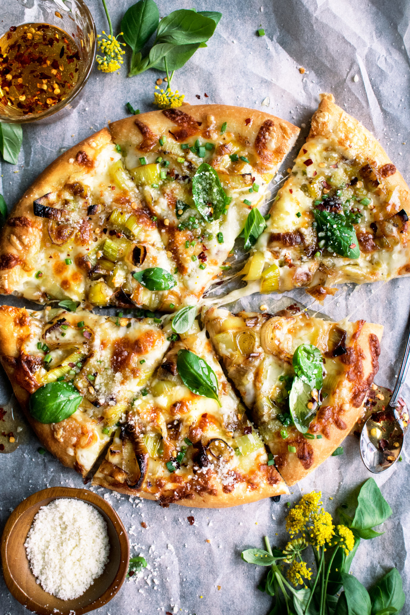 A caramelized leek pizza cut into six slices and topped with fresh basil