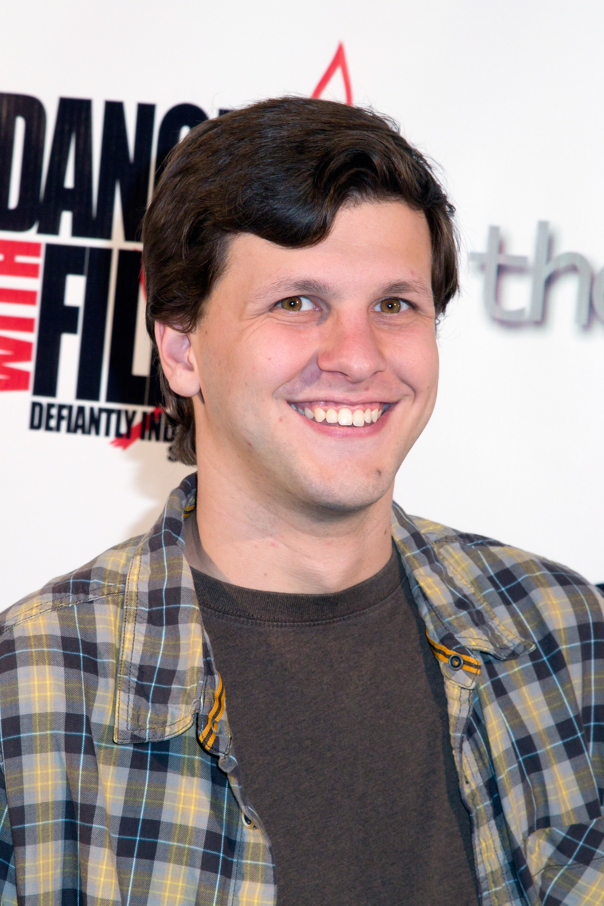 Dyllan smiling at a media event and wearing a plaid top