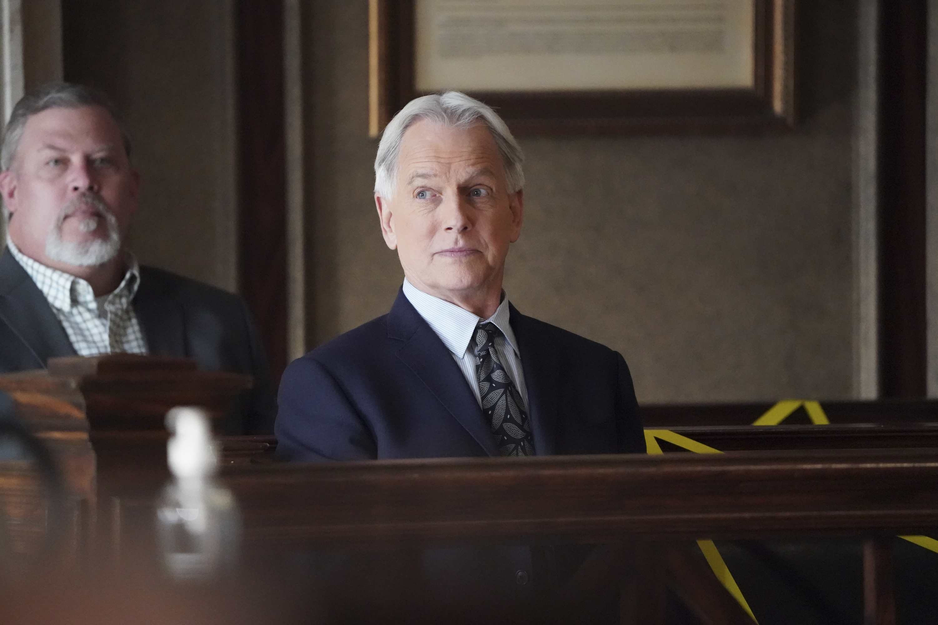 Close-up of Mark in a courtroom in a suit and tie from a TV show