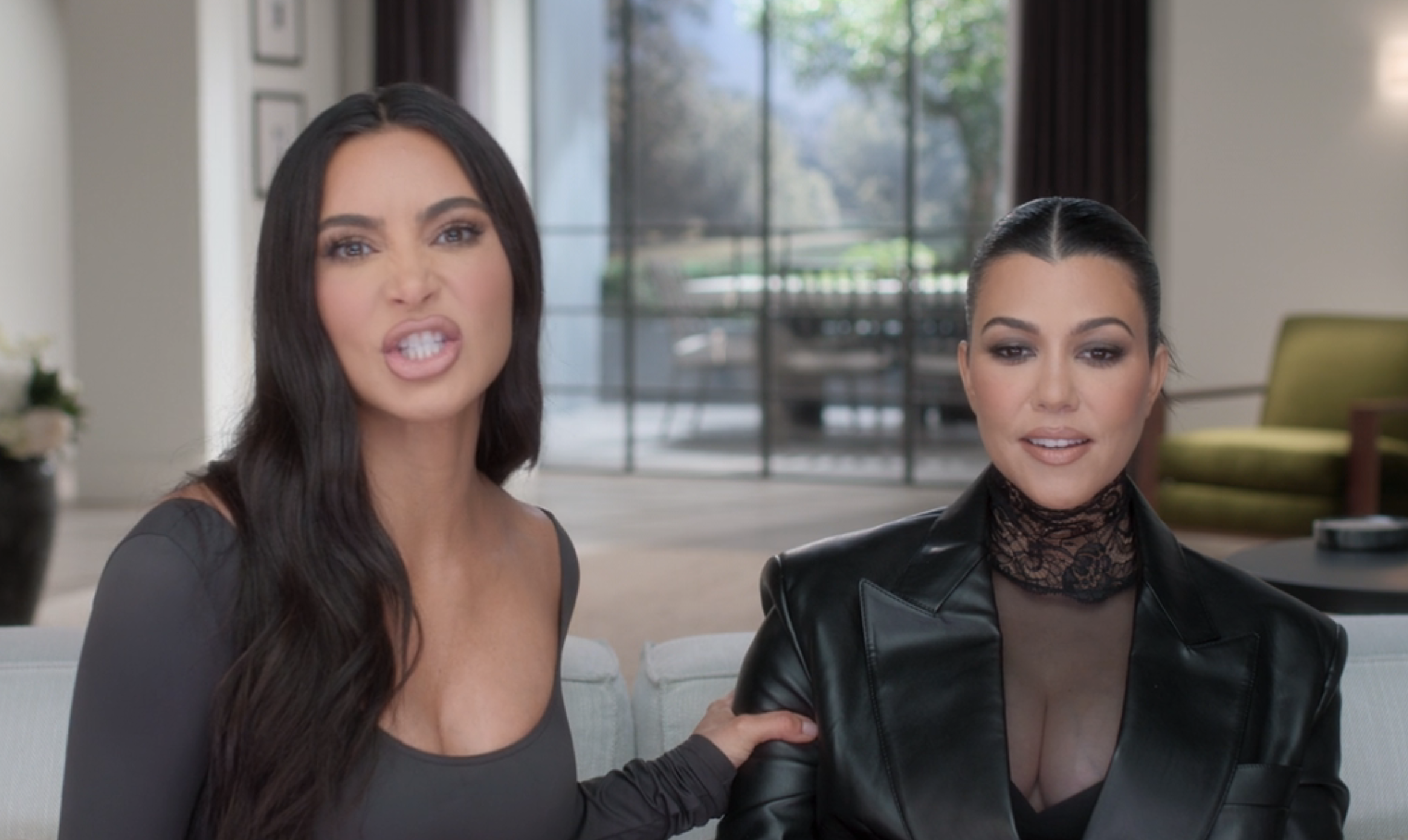 Close-up of Kim and Kourtney sitting together and Kim grabbing Kourtney's arm