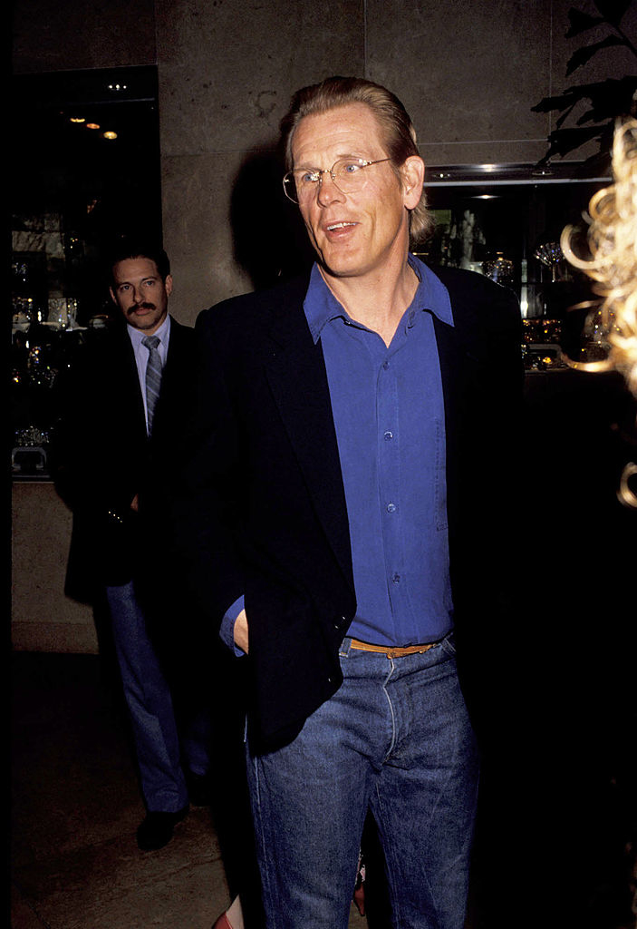Close-up of Nick wearing glasses and dressed casually in jeans and a suit jacket and shirt