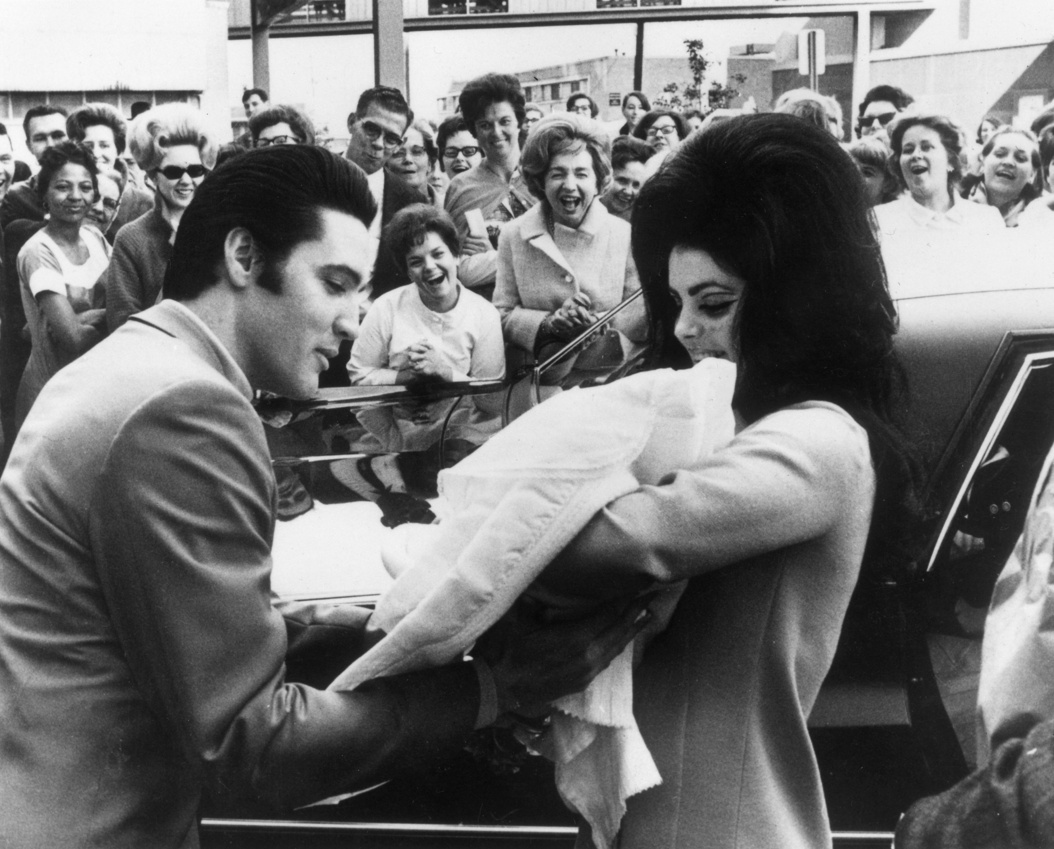 The real Elvis and Priscilla with baby Lisa Marie in front of a crowd of fans