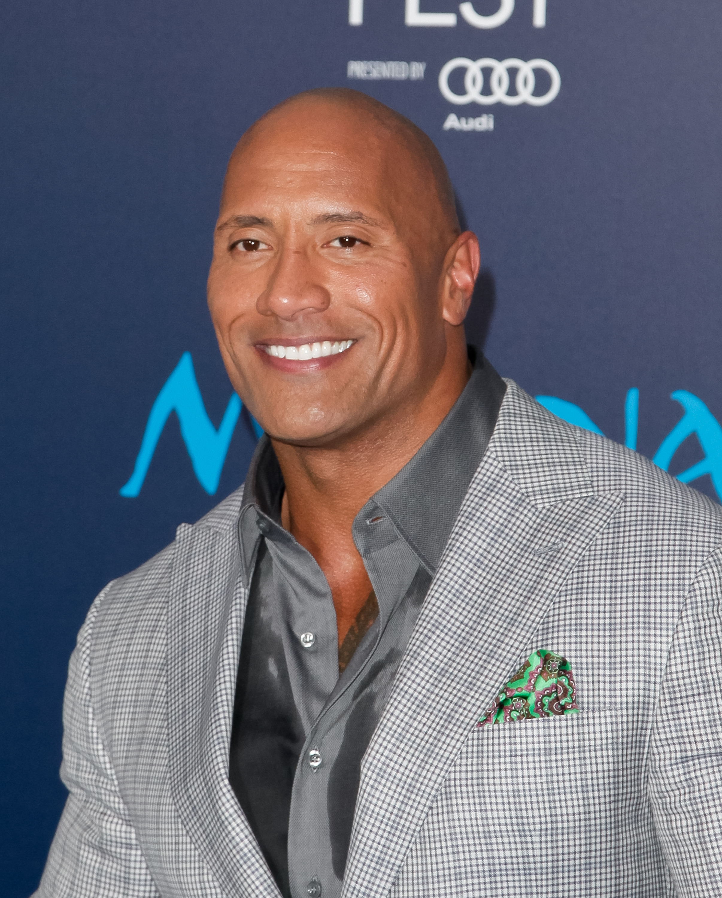 Close-up of Dwayne smiling in a shirt and jacket at a media event