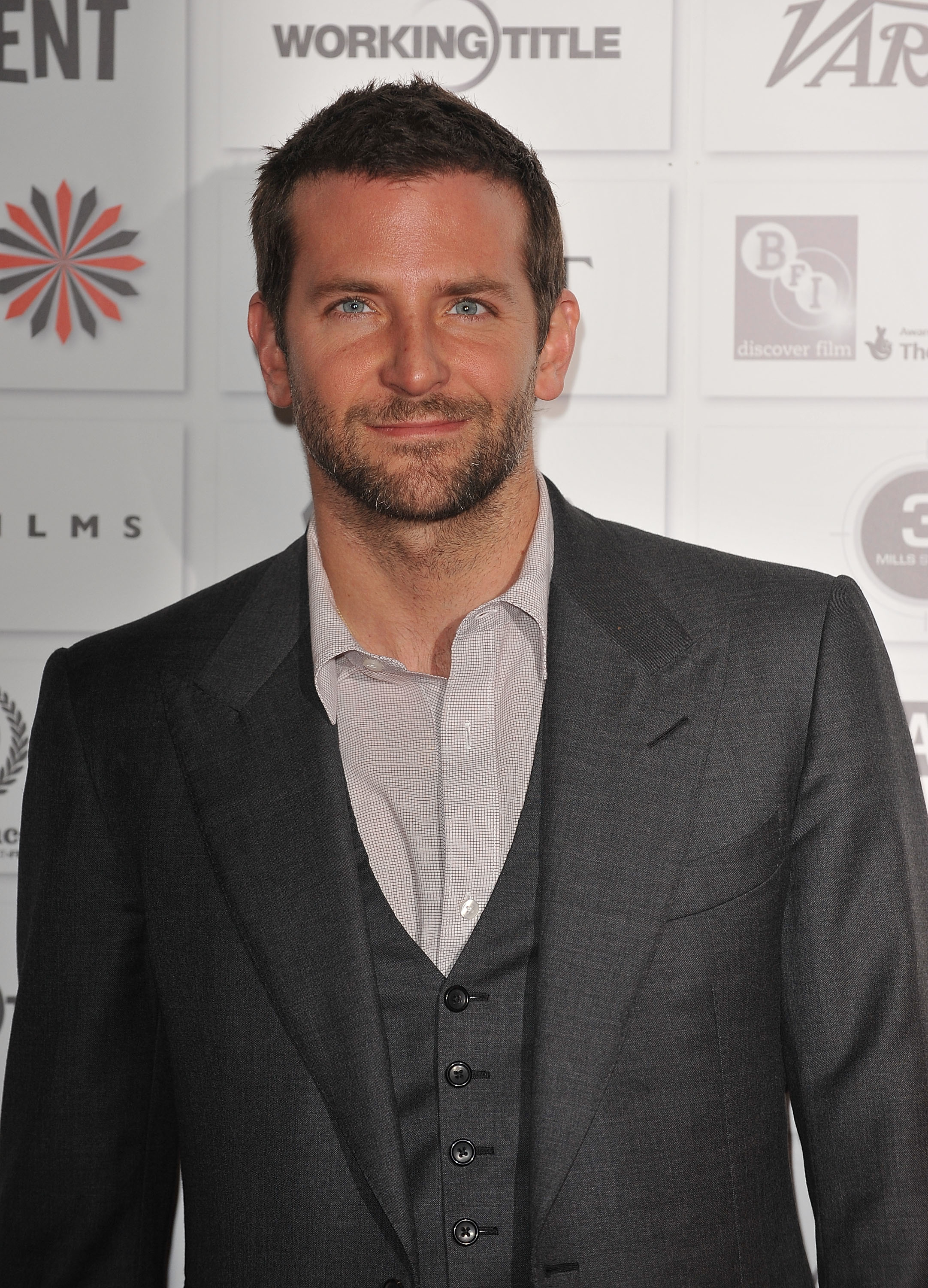 Close-up of Bradley smiling in a three-piece suit at a media event