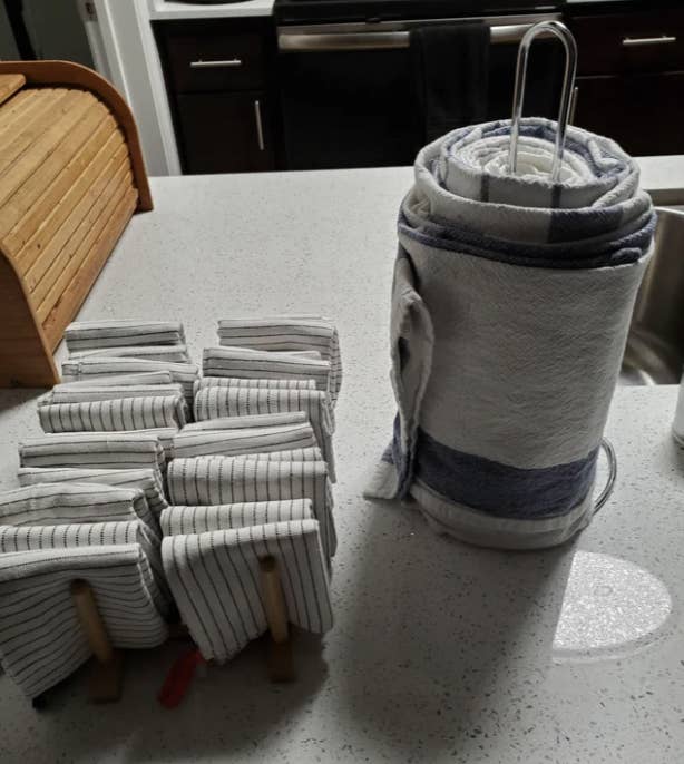 cloth napkins in a napkin holder next to cloth towels wrapped around a paper towel holder