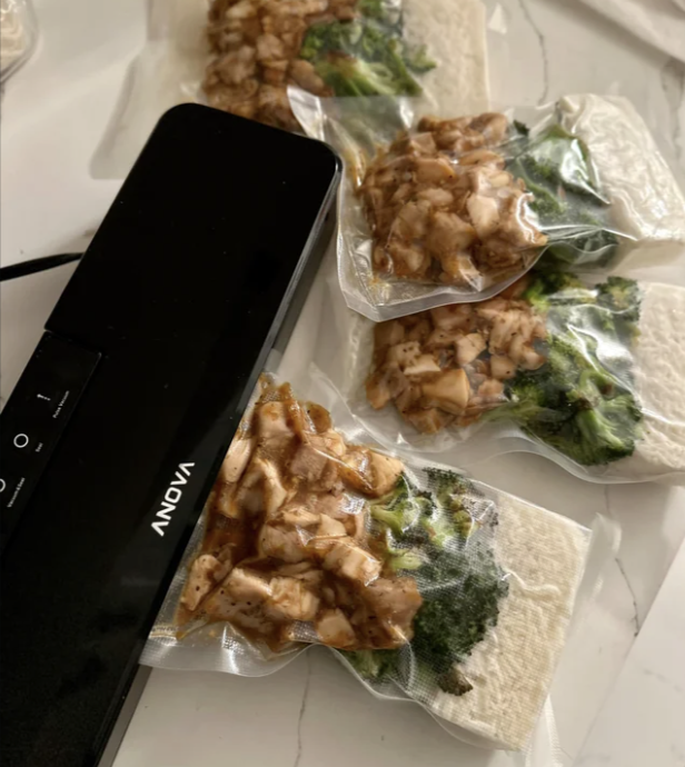 vacuum sealer and four meal prep bags filled with chicken rice and broccoli