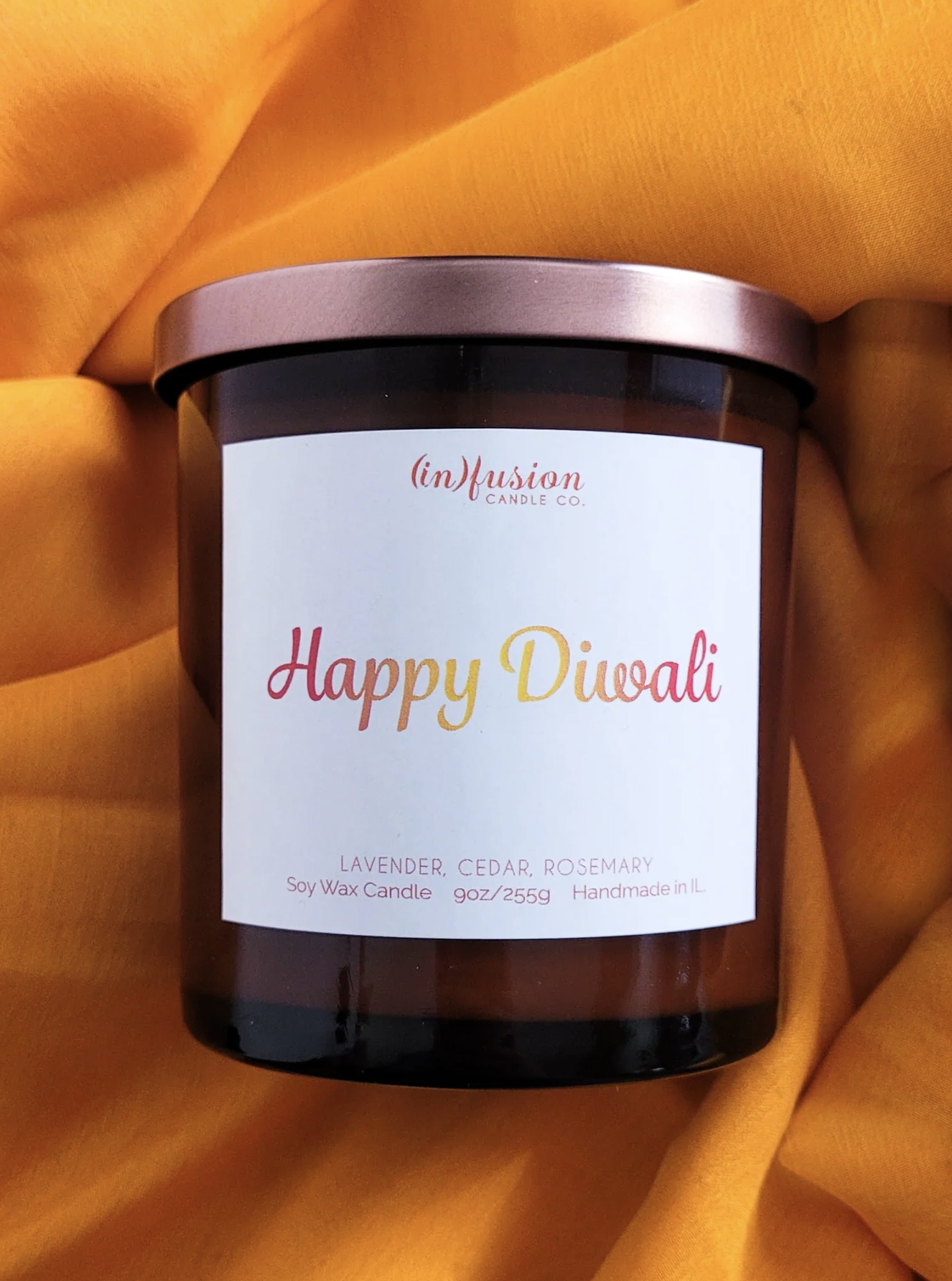 Lavender candle with saying &quot;Happy Diwali&quot; on orange fabric