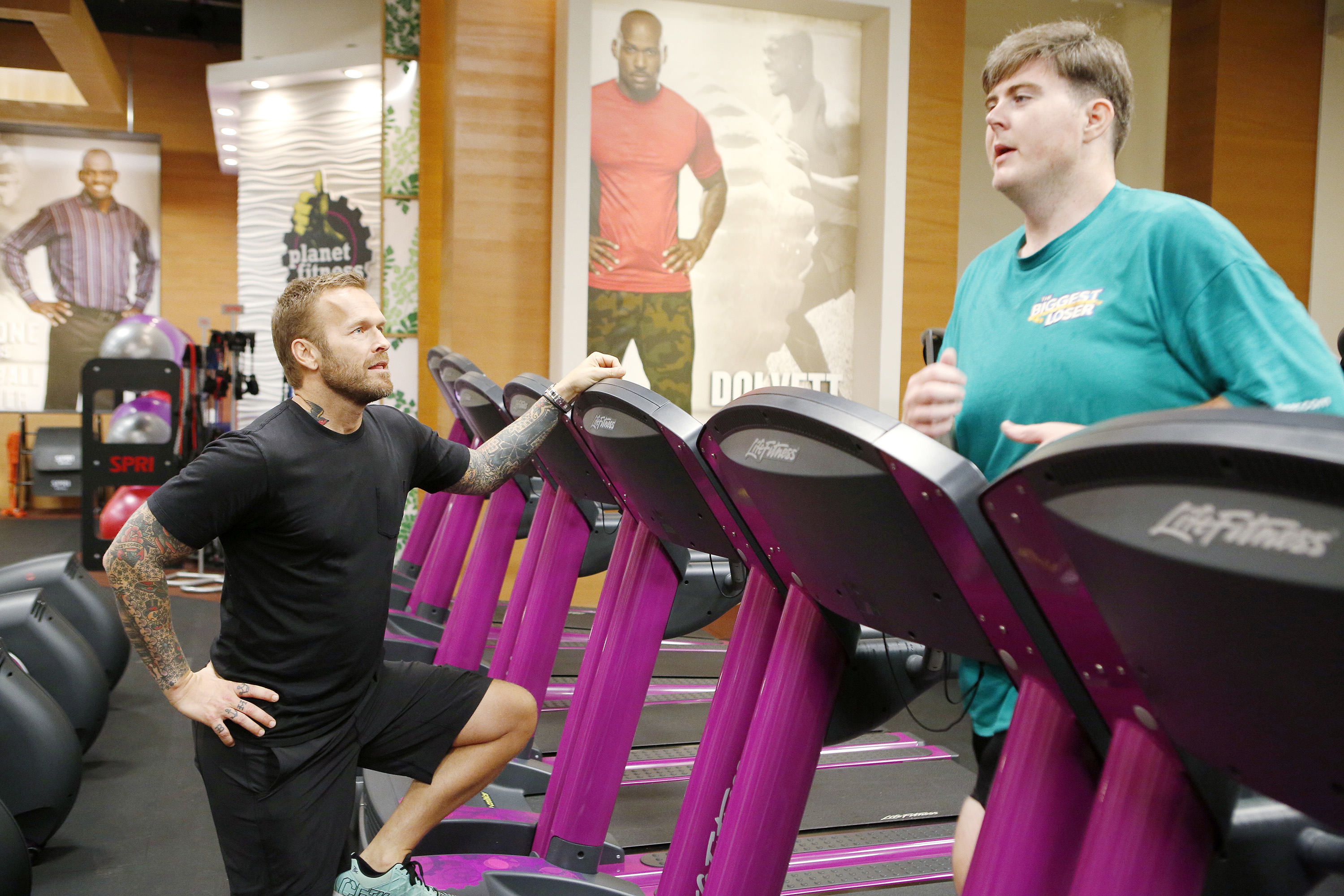 A contestant on the biggest loser running on a treadmill while a trainer watches