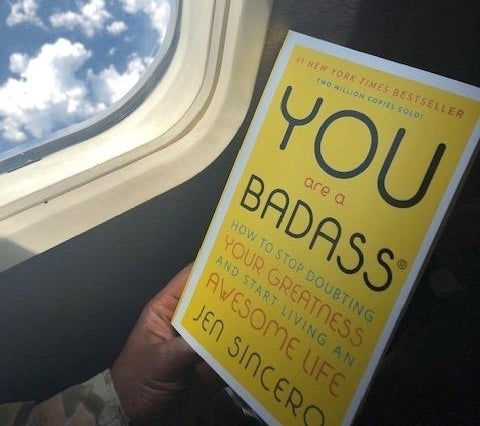 a reviewer photo of a person holding the book on a plane