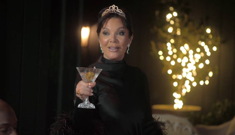 Close-up of Kris holding a glass and wearing a crown