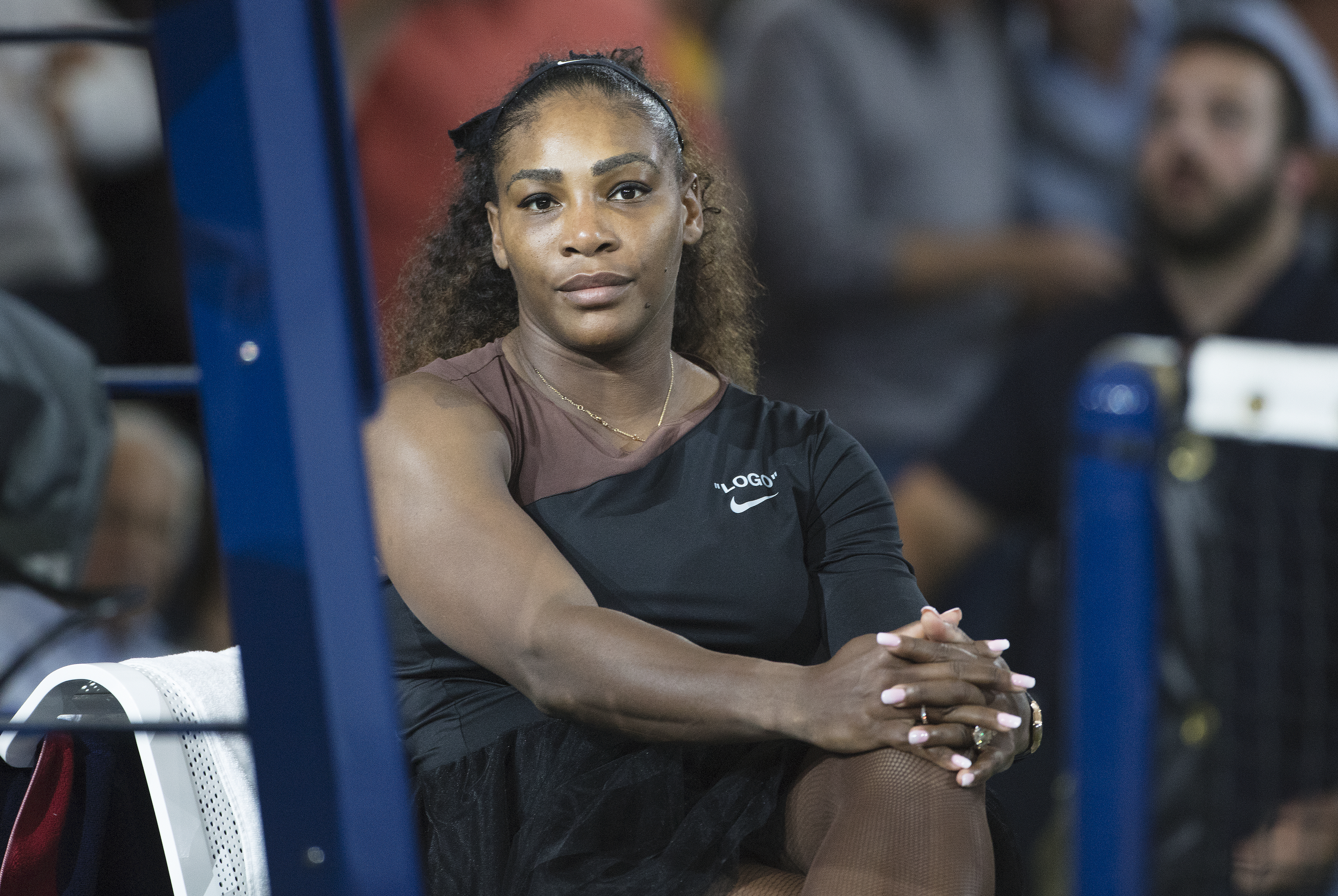 Serena sitting and wearing an off-the-shoulder athletic outfit
