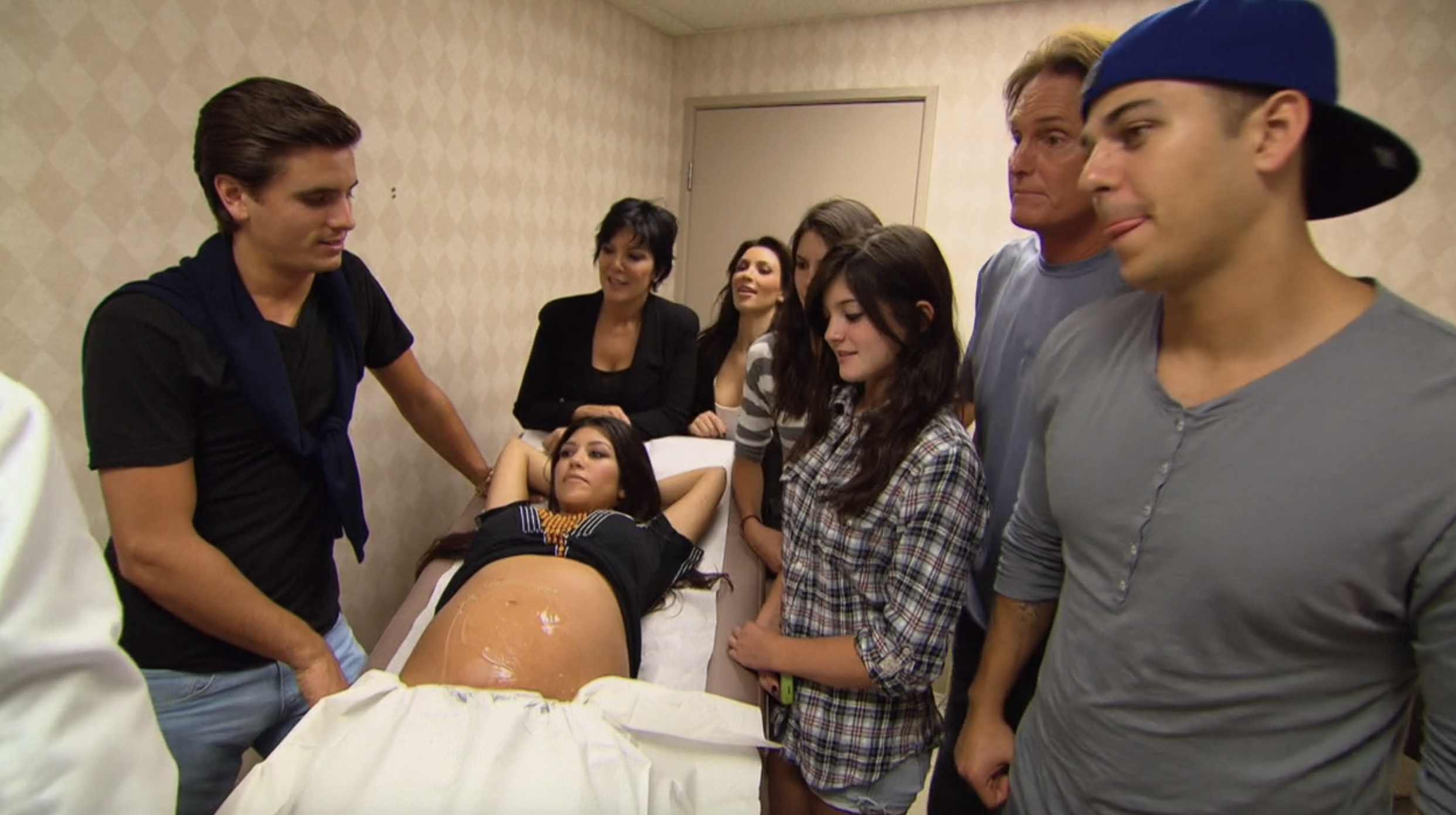 Screenshot of a pregnant Kourtney in bed and surrounded by her family