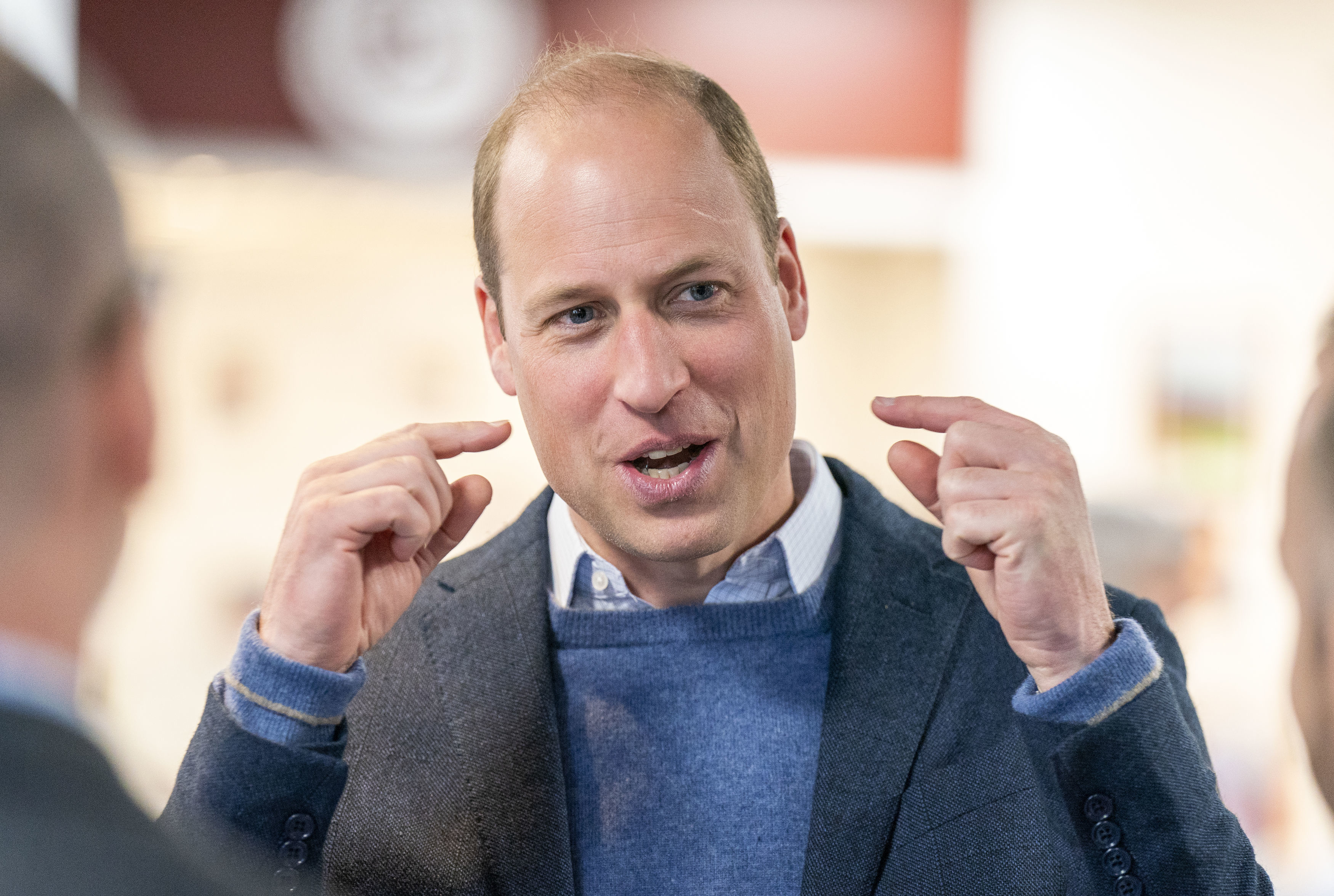 Close-up of William gesturing in a sweater and jacket
