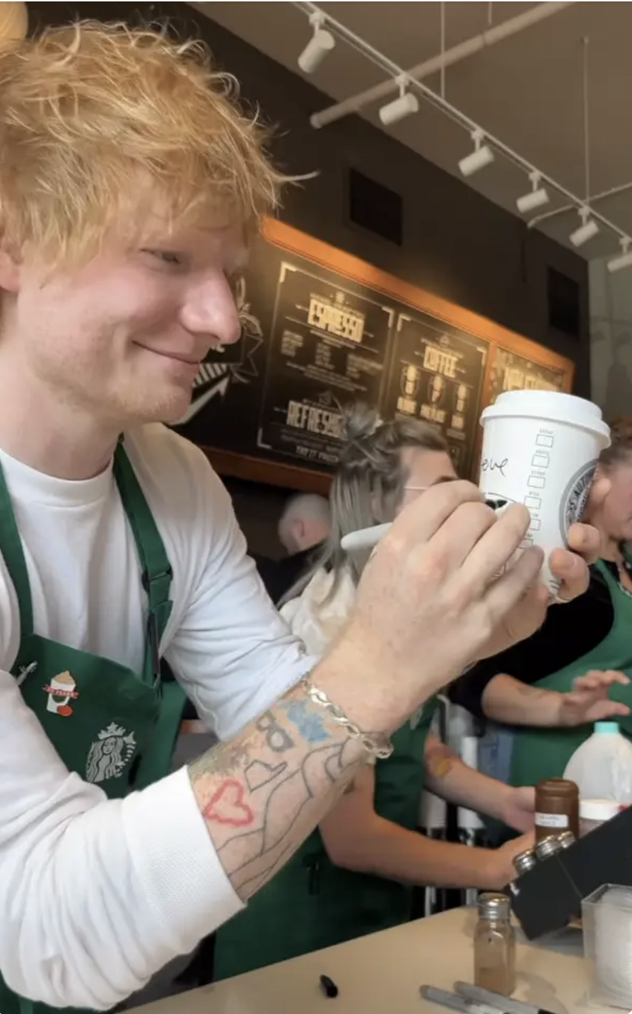 him in an apron writing a name on a coffee cup