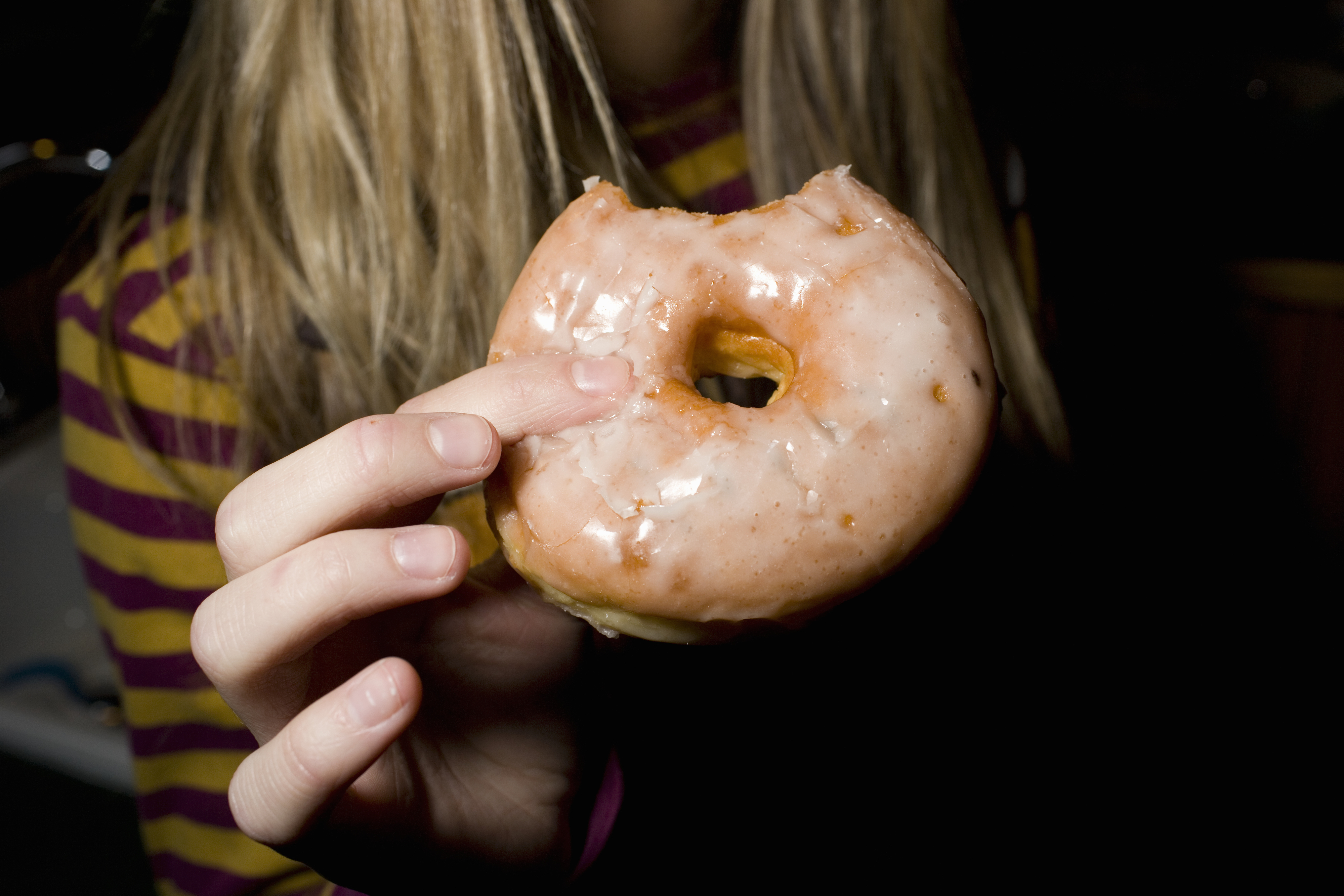 A person holding a donut with a bite taken out of it