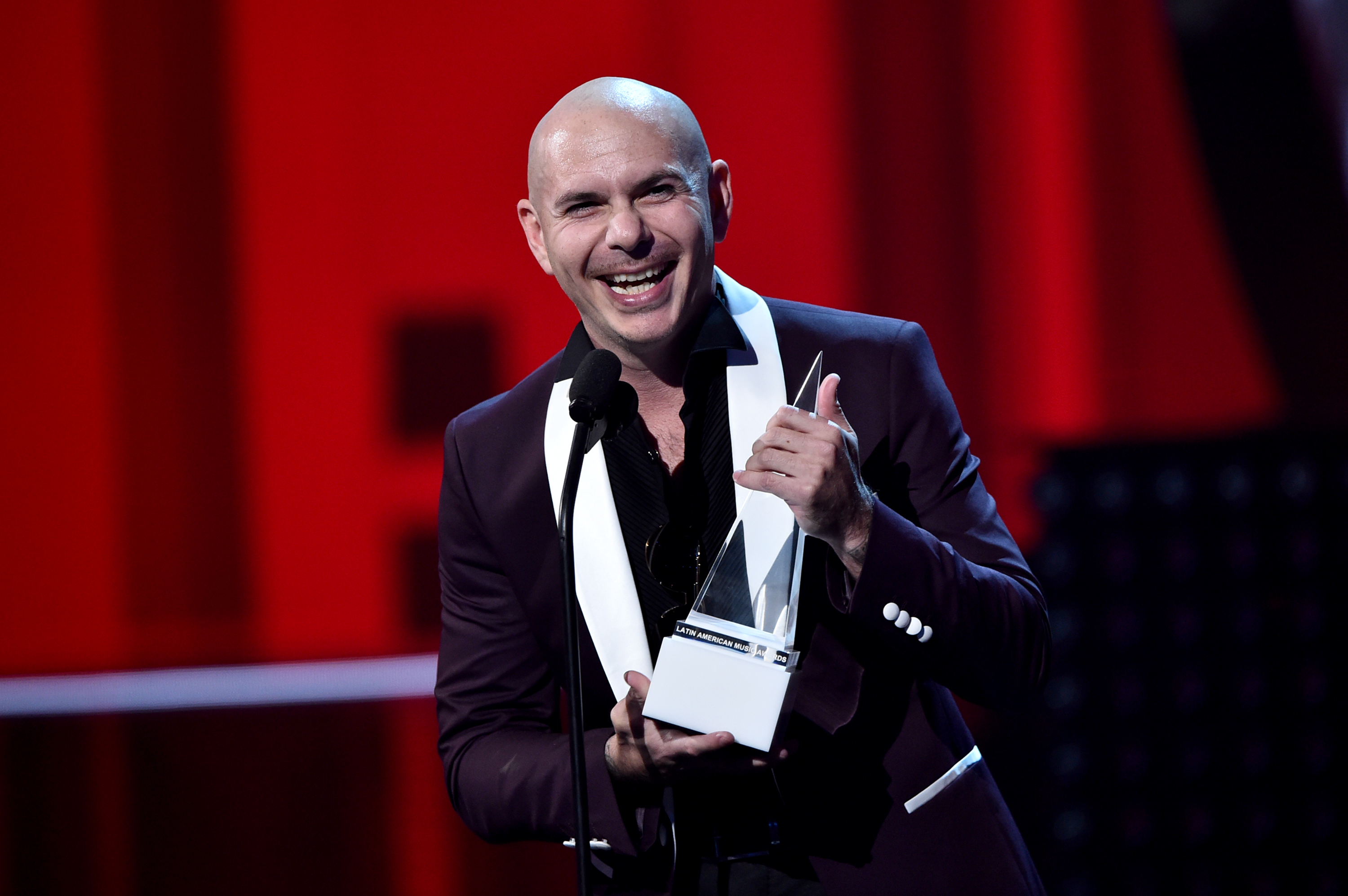 Pitbull smiling and holding an award
