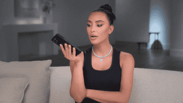 Kim Kardashian holds her phone and gasps before giggling.