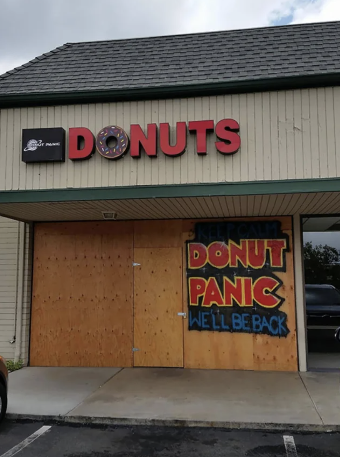 donut panic we&#x27;ll be right back written on a boarded up building