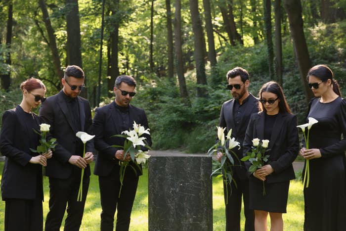 People holding flowers at a grave