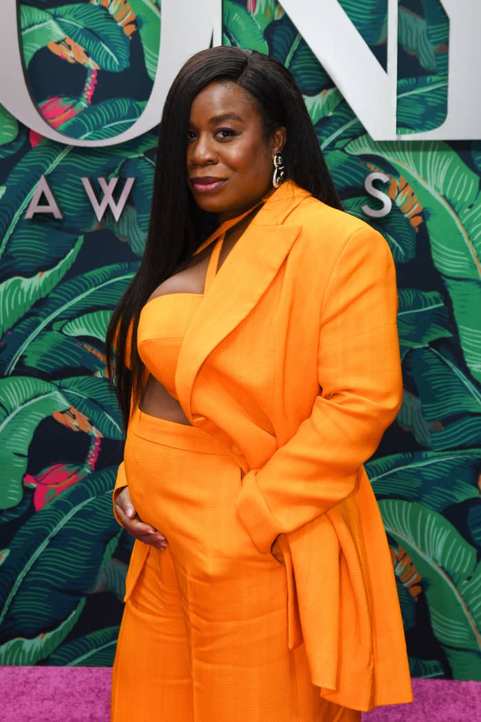 Closeup of Uzo Aduba holding her small baby bump in a crop top and matching pants