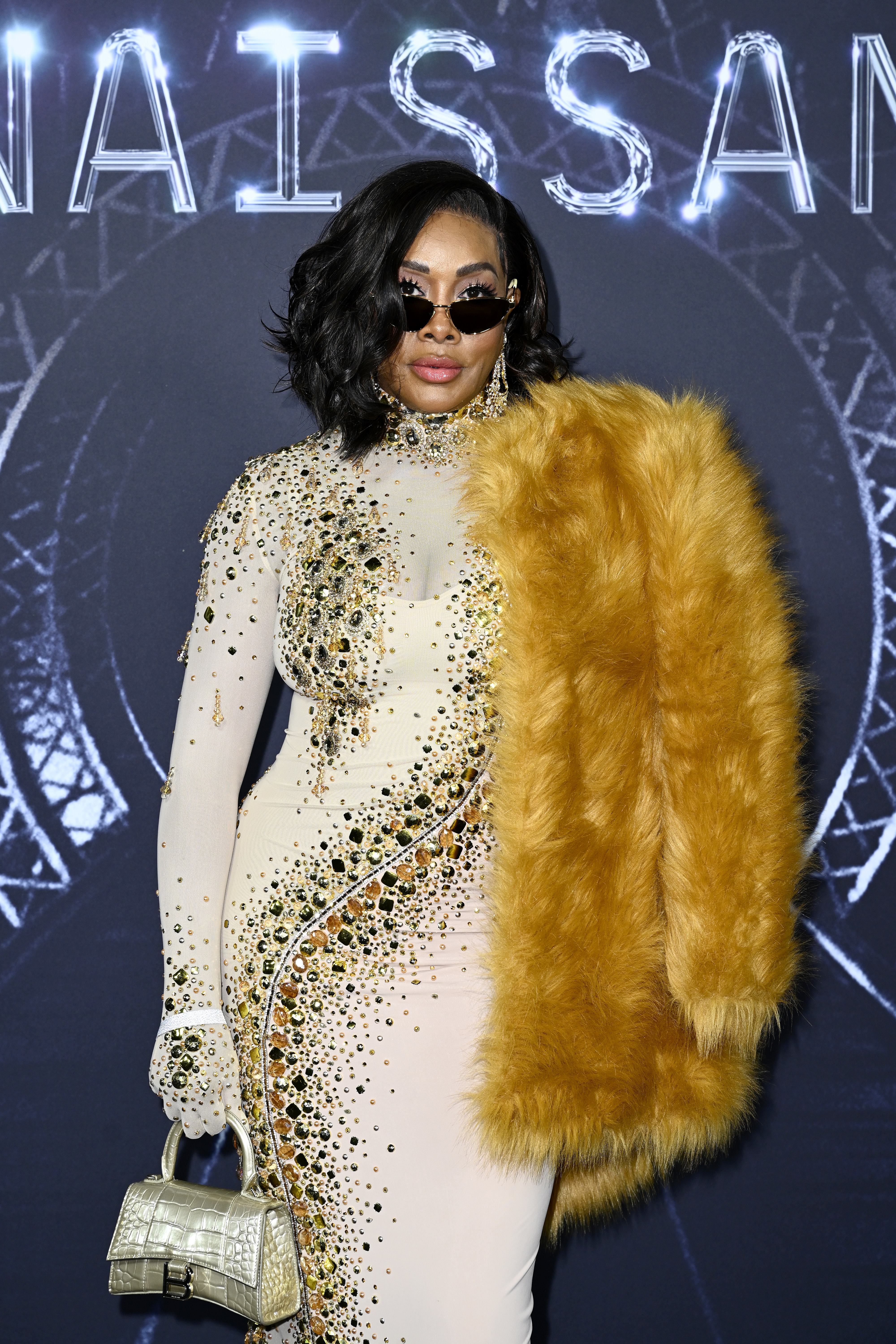 Vivica in a long-sleeved, jewel-swirl dress and furry jacket