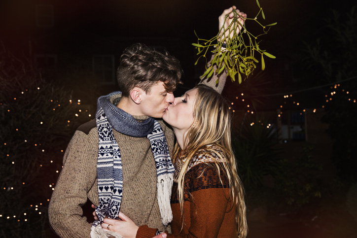 couple kissing underneath mistletoe