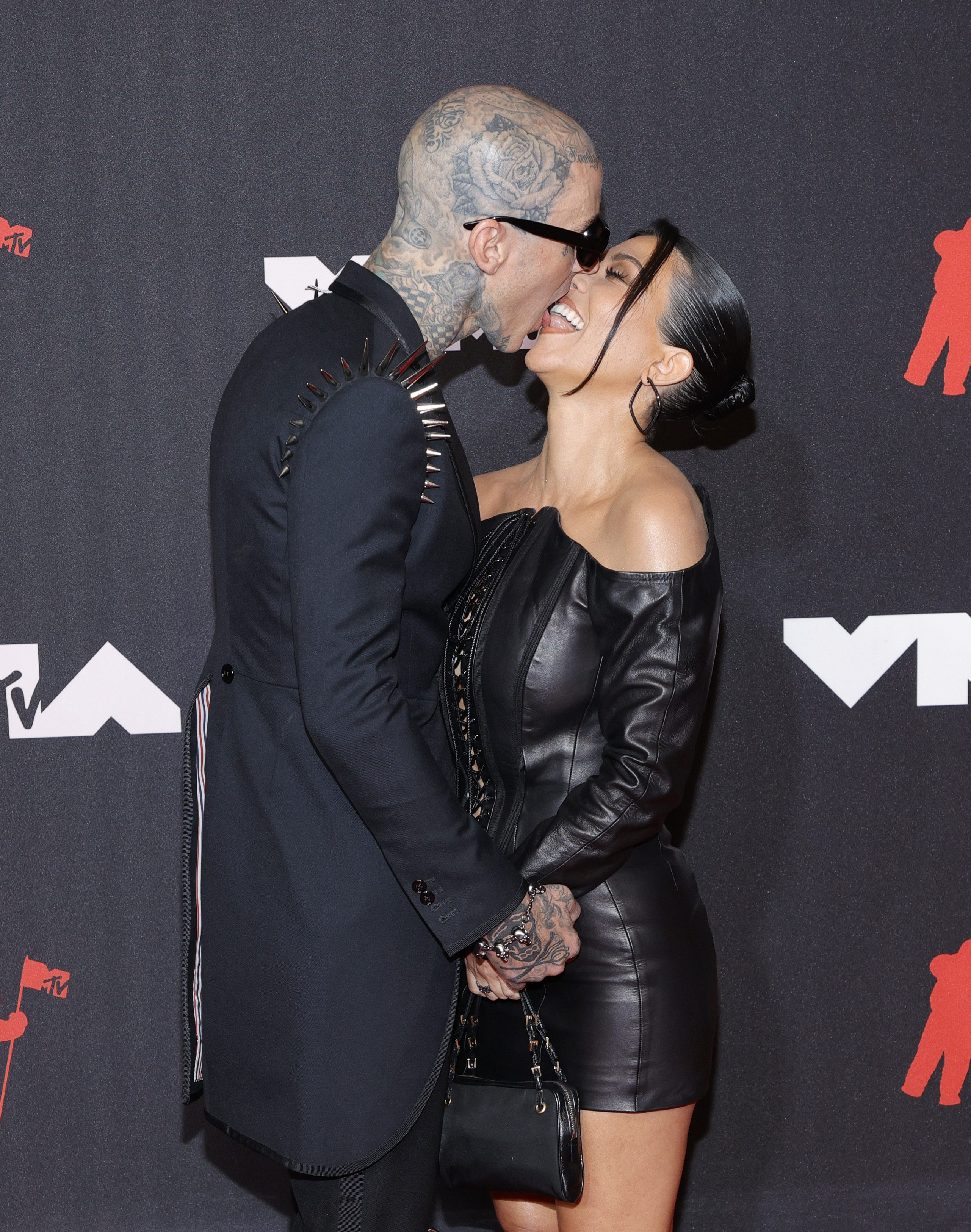 Close-up of Kourtney and Travis tongue kissing at a media event